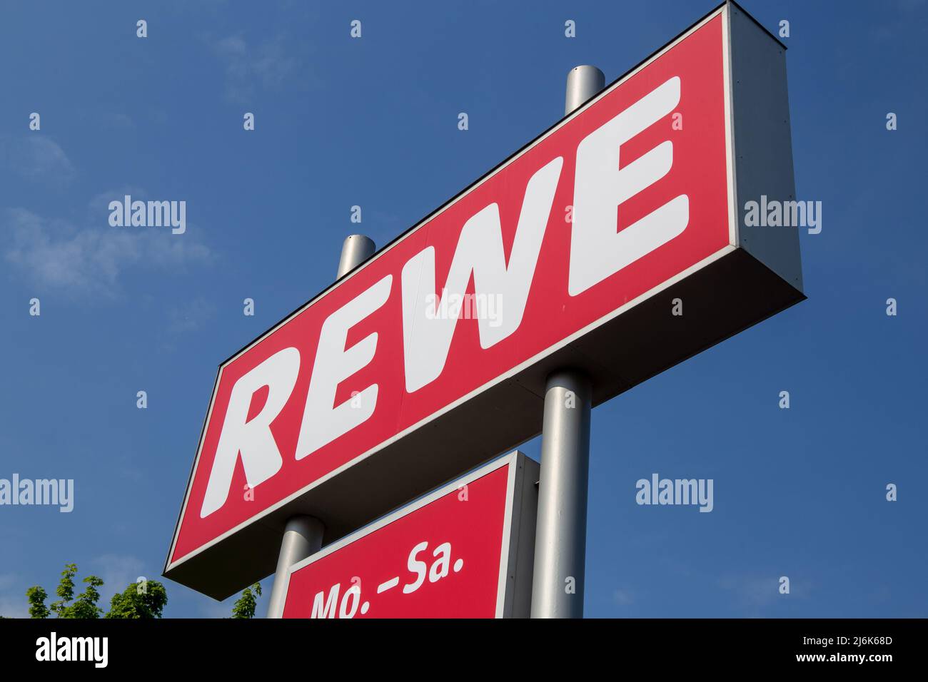 Logo of retail chain REWE (Germany) in front of blue sky Stock Photo