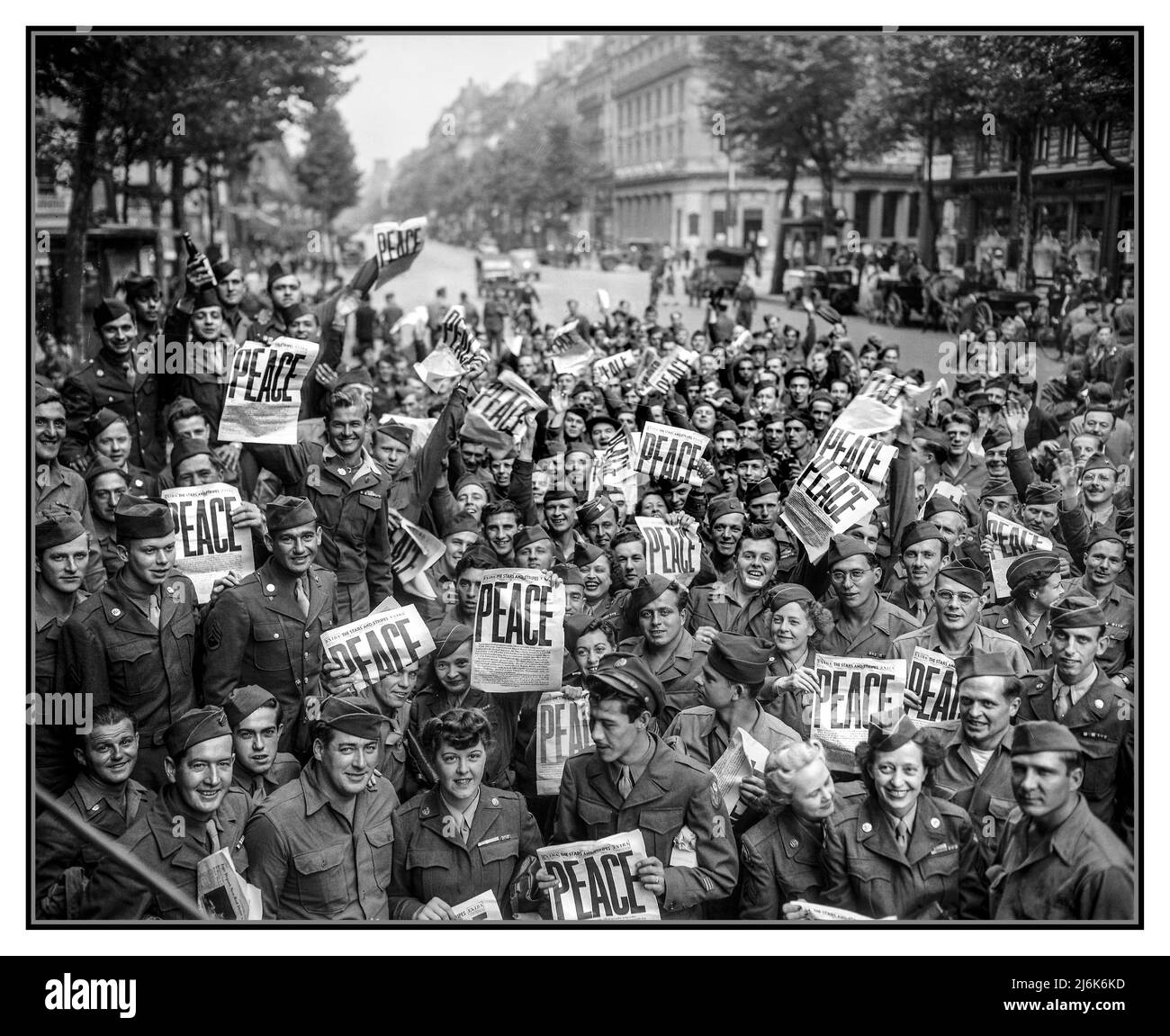 VJ DAY PARIS 1945 American servicemen and women gather in front of 'Rainbow Corner' Red Cross club in Paris to celebrate the unconditional surrender of the Japanese. ‘PEACE’ headline on the US military newspaper 'Stars and Stripes' being held by ecstatic uniformed USA military personnel.  VJ Day (Victory over Japan Day) marks the official end of World War II, when Japan formally surrendered to -Allied forces. This momentous occasion celebrated on August 15, 1945 (the day Japan announced its surrender) & September 2, 1945 (day surrender documents were signed aboard USS Missouri Tokyo Bay Stock Photo