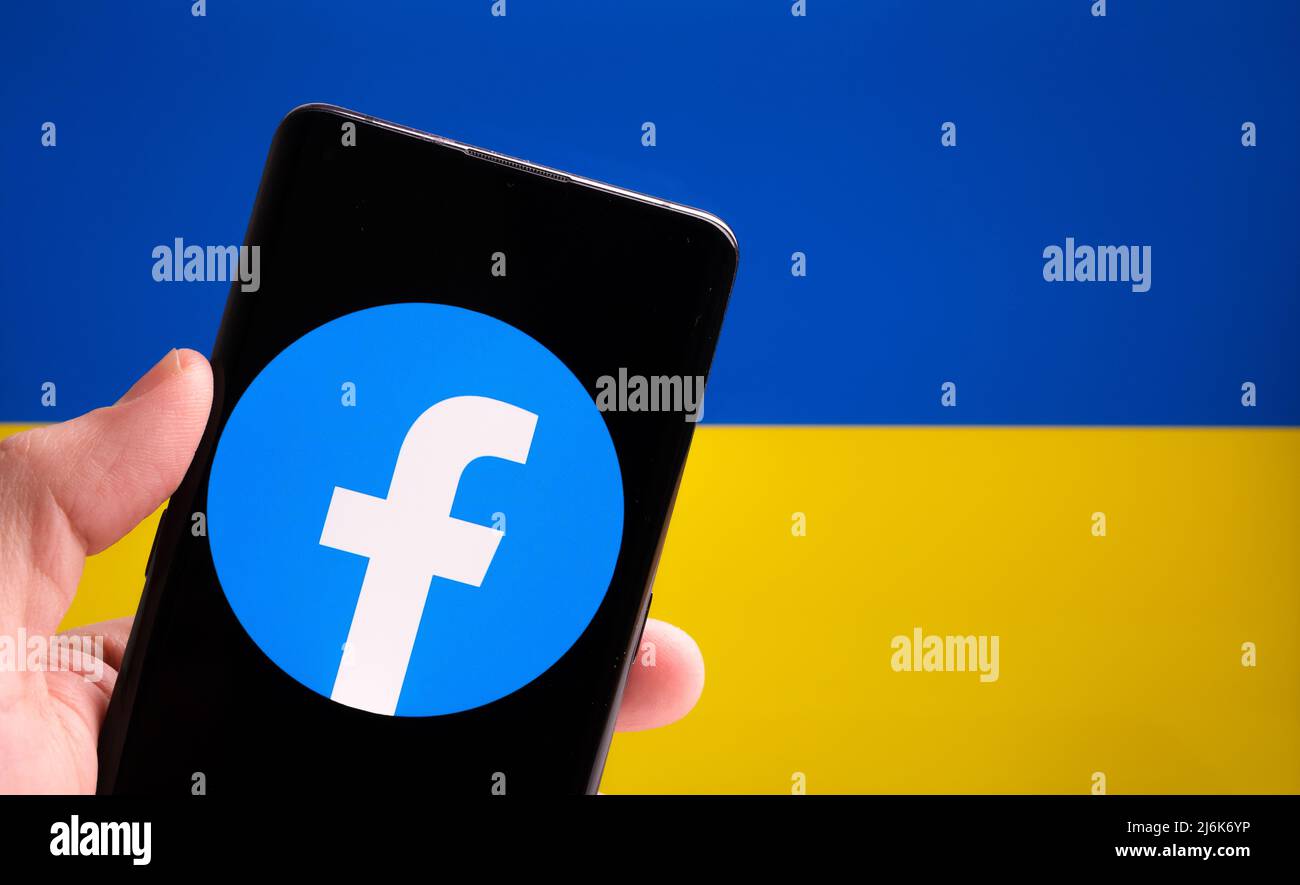 Facebook app logo on smartphone and Ukrainian flag on the background. Concept. Stafford, UK, March 20, 2022 Stock Photo