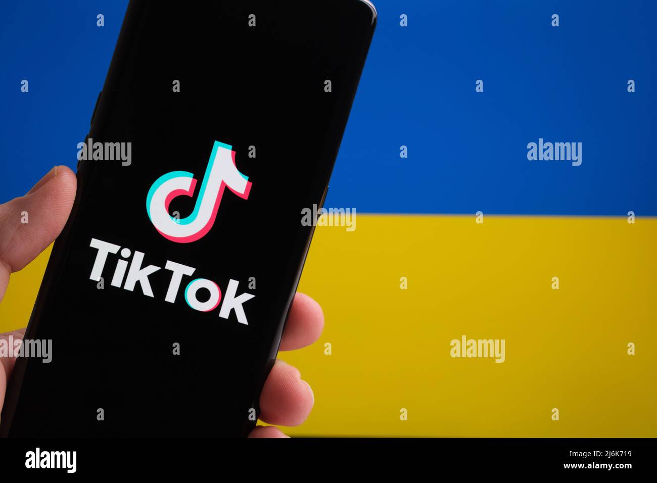 TikTok app logo on smartphone and Ukrainian flag on the background. Concept. Stafford, UK, March 20, 2022 Stock Photo