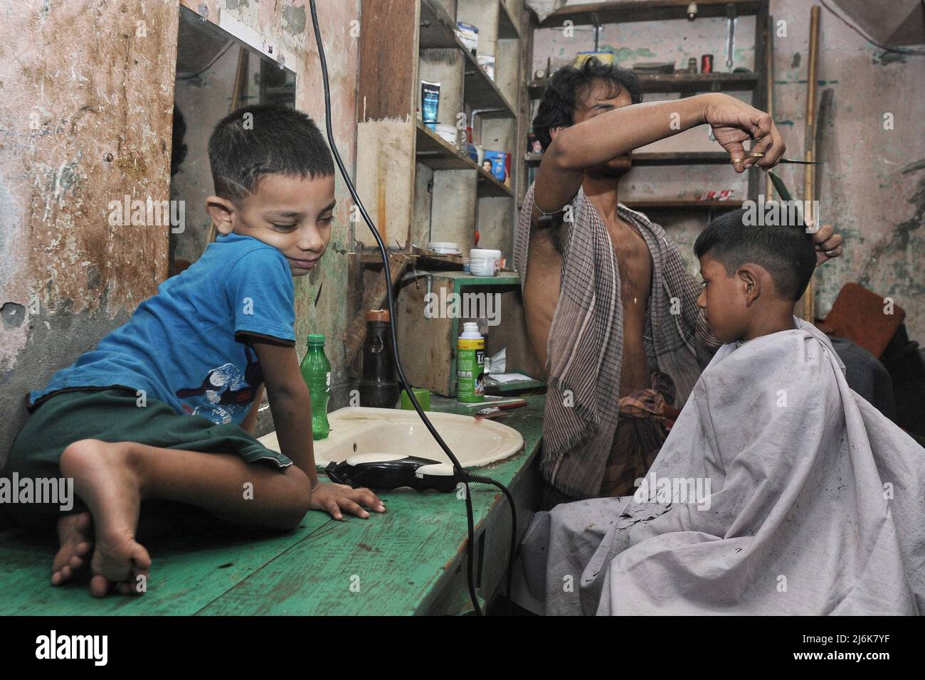 Dhaka, Bangladesh. 2nd May 2022. Children getting a haircut at a barber shop at the Bihari Camp for Eid al-Fitr. Also known as the Geneva camp, it has about 50 thousand Urdu speaking Indian & Pakistani people living at the camp. The Bihari minority remain some of Bangladesh’s most marginalized communities. Credit: Majority World CIC/Alamy Live News Stock Photo