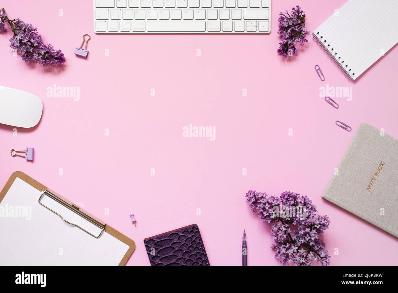 Keyboard and mouse, notebooks, pen, a bouquet of lilacs on a pink ...