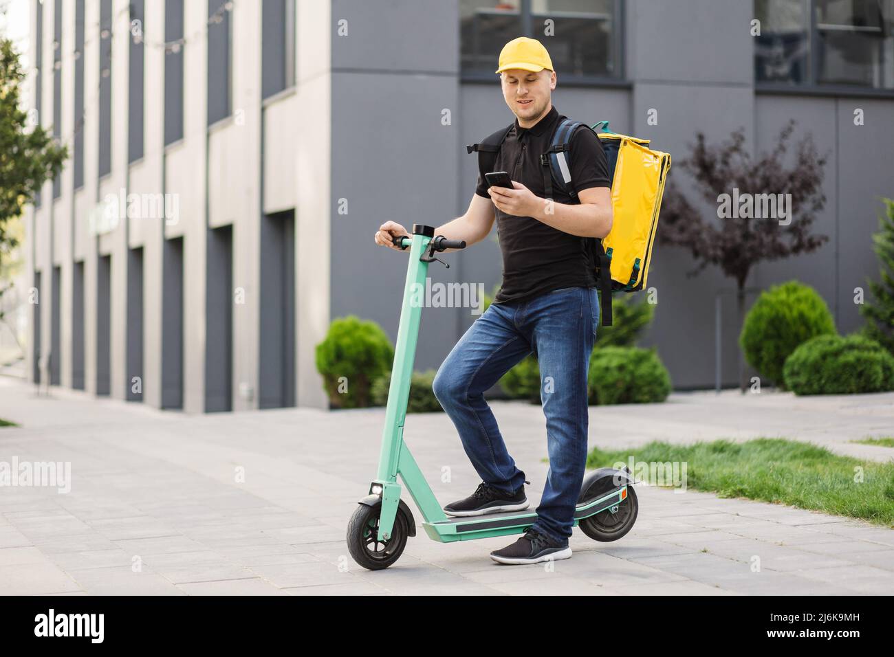 Food delivery man with thermo backpack holding mobile phone waiting ...