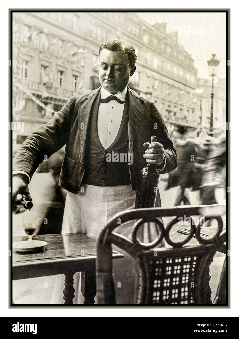 Paris Waiter 1900s Vintage Retro B&W serving wine at street cafe restaurant boulevard wearing typical french waiter uniform, pouring a glass of red wine outside alfresco reportage Paris France Stock Photo
