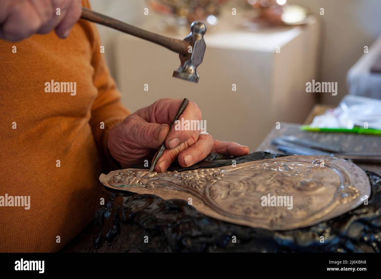 Engraving a silver plate with hammer and chisel. Stock Photo
