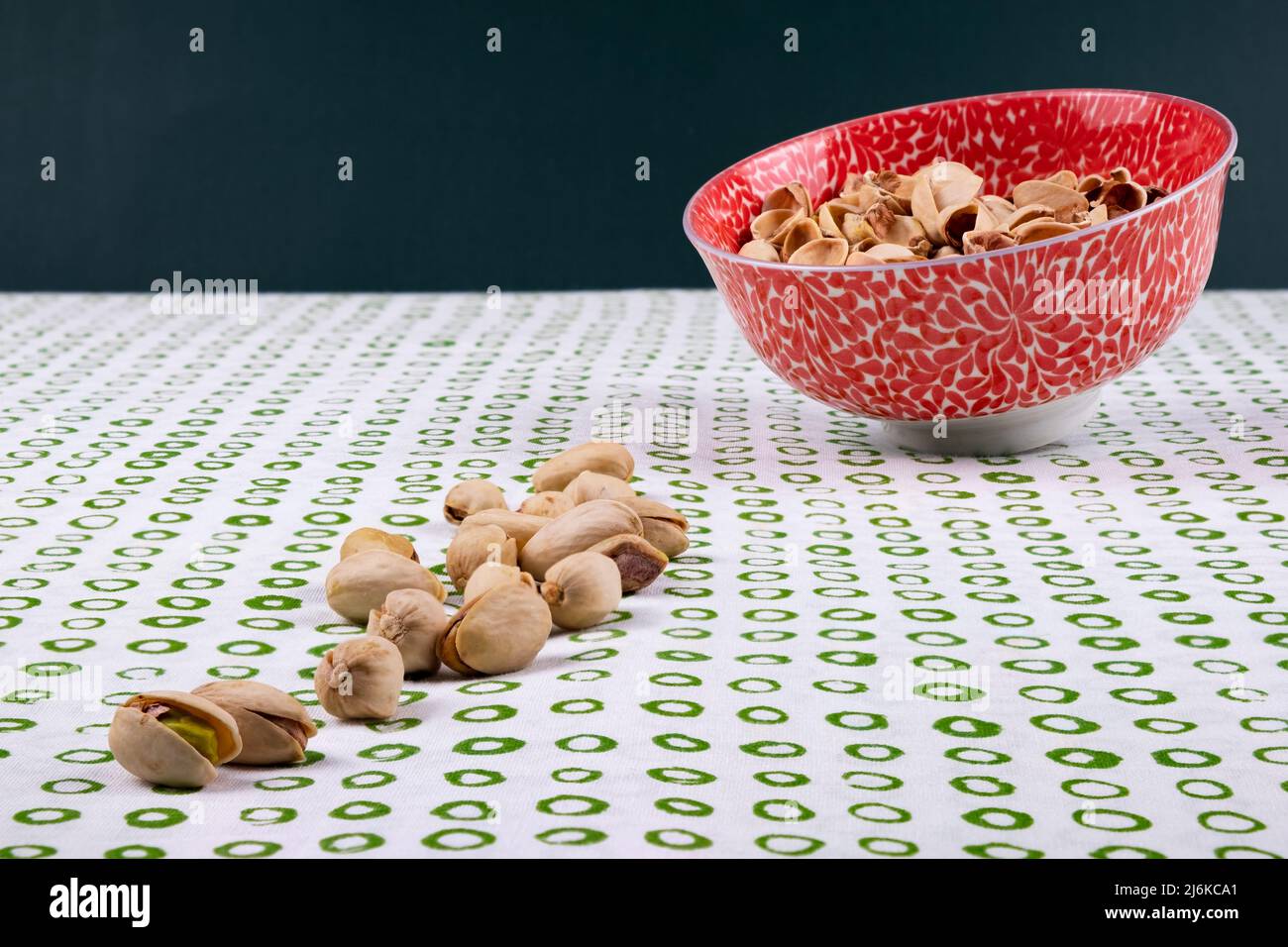 Organic pistachio shells in a flowery bowl on top of a white table with