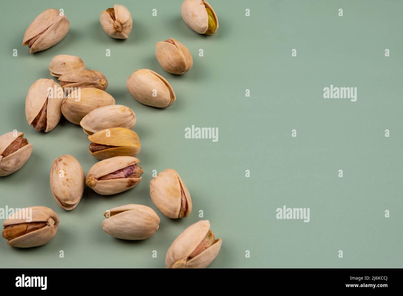 Tasty organic pistachios on a green table, with copy space Stock Photo