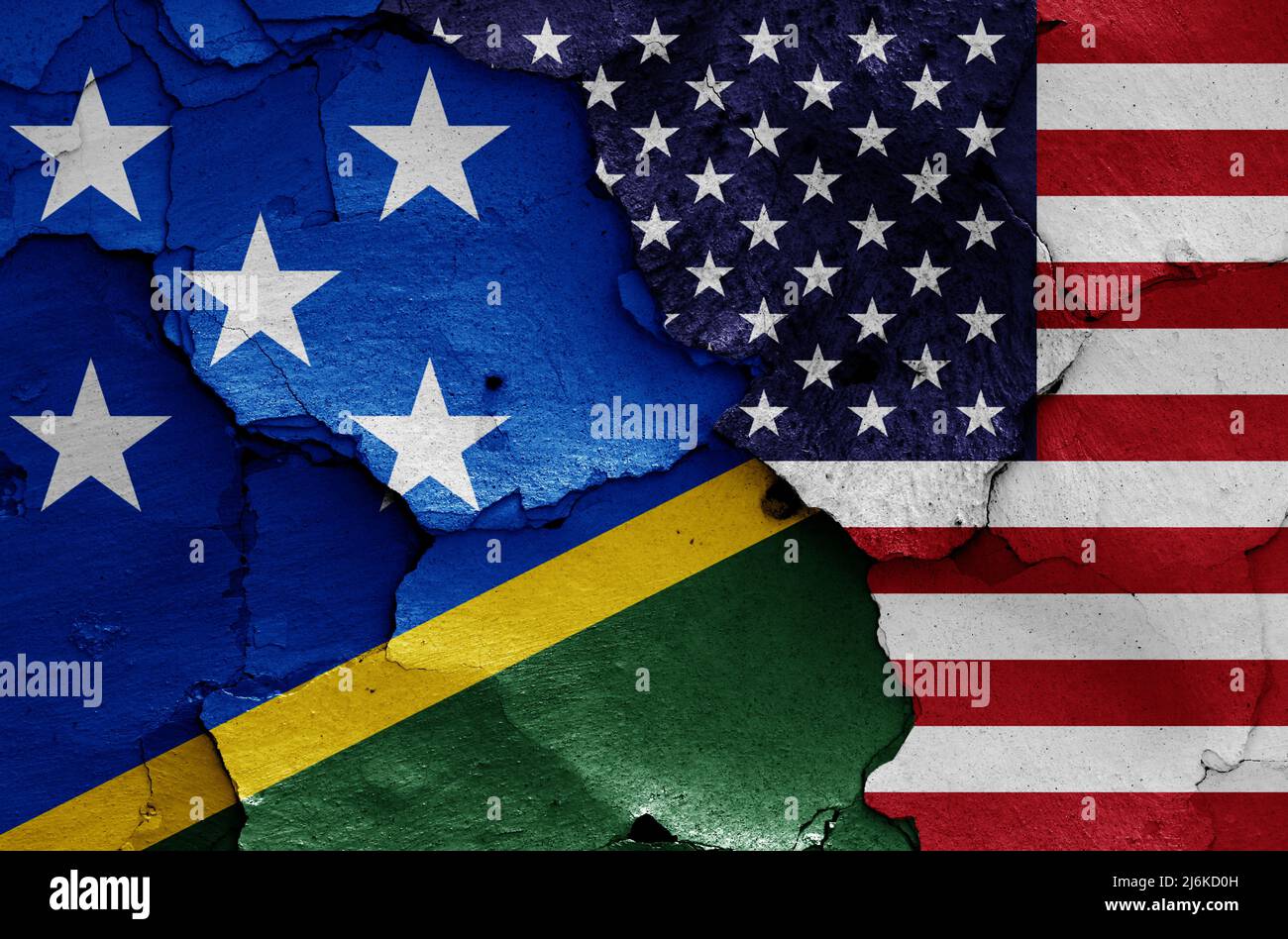 flags of Solomon Islands and USA painted on cracked wall Stock Photo