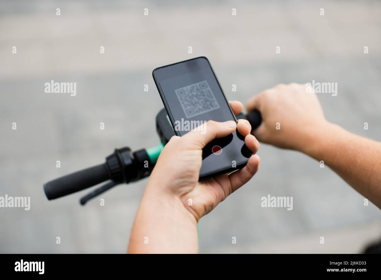 Man scan QR code by smart phone to unlock and rent electric push