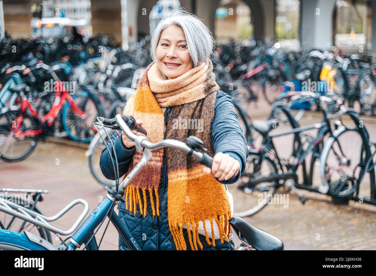 Senior woman gets the bike in a parking Stock Photo