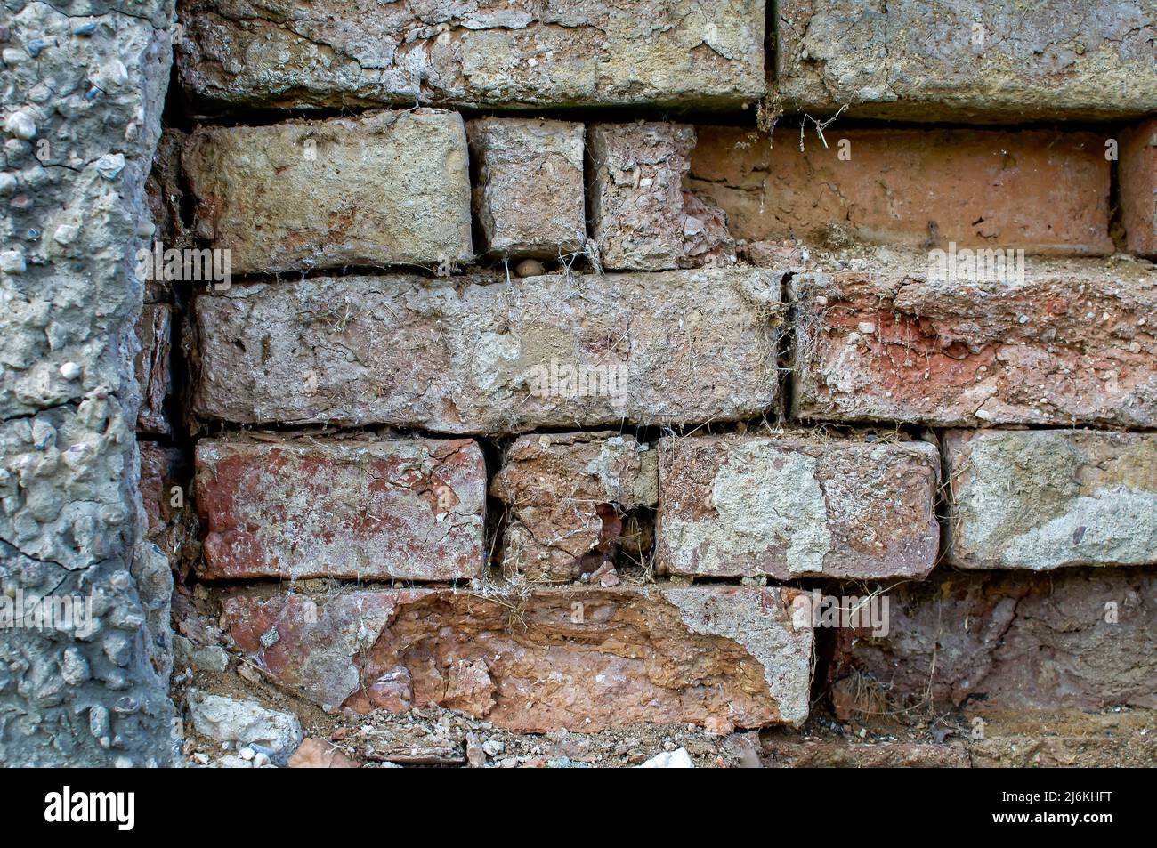 texture of an old wall, a wall made of damaged colored brick, with defects in plaster, cobwebs, background, wallpaper for projects Stock Photo