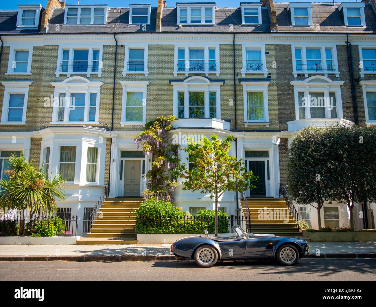 London - April 2022: An AC Cobra sports car parked outside attractive street of terraced houses Stock Photo