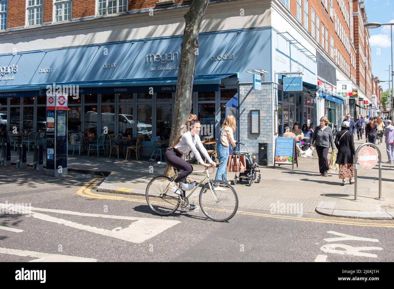 London - April 2022: A cyclist outside Megans on High Street Kensington Stock Photo