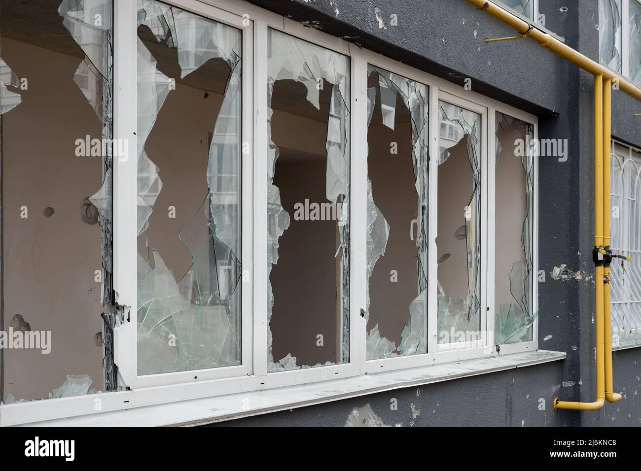 Aftermath bombed building window shatter glass damage building destruction Ukraine war Russia shooting civilian shell. Smashed window broken glass Stock Photo