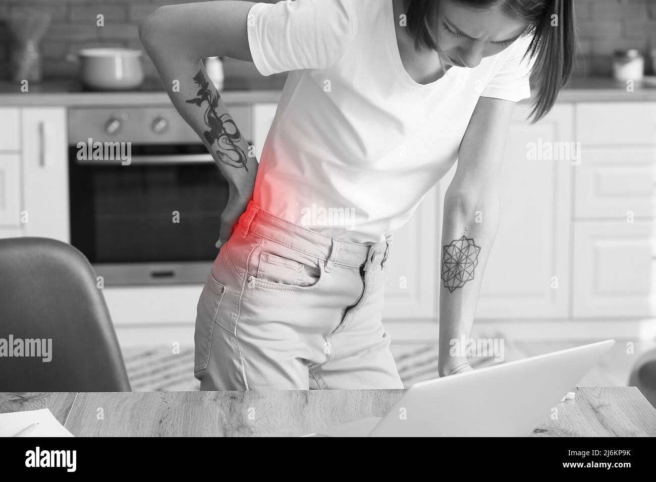 Young woman feeling back pain in kitchen Stock Photo