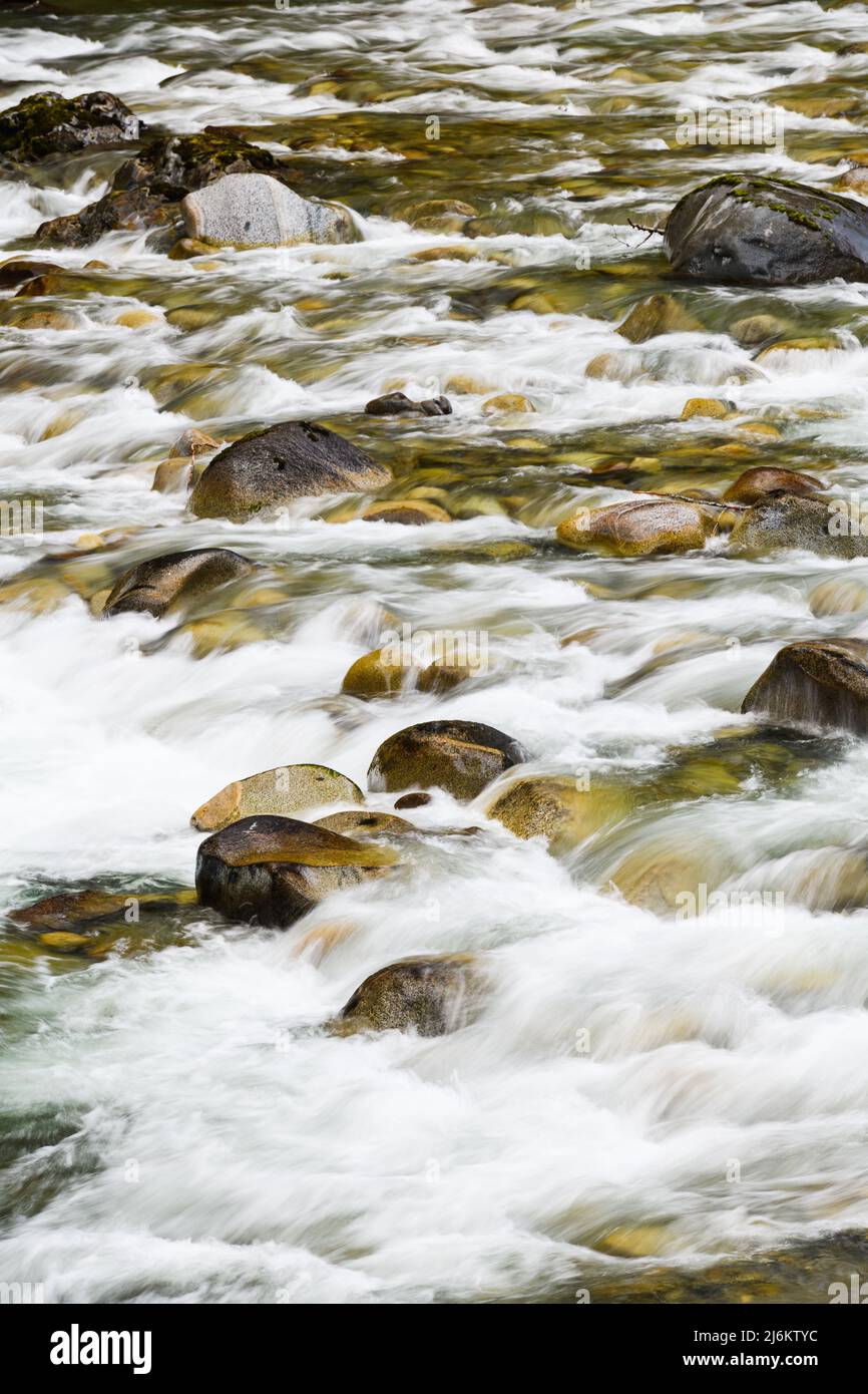 Rocks in the riverbed break a flowing river into white water 