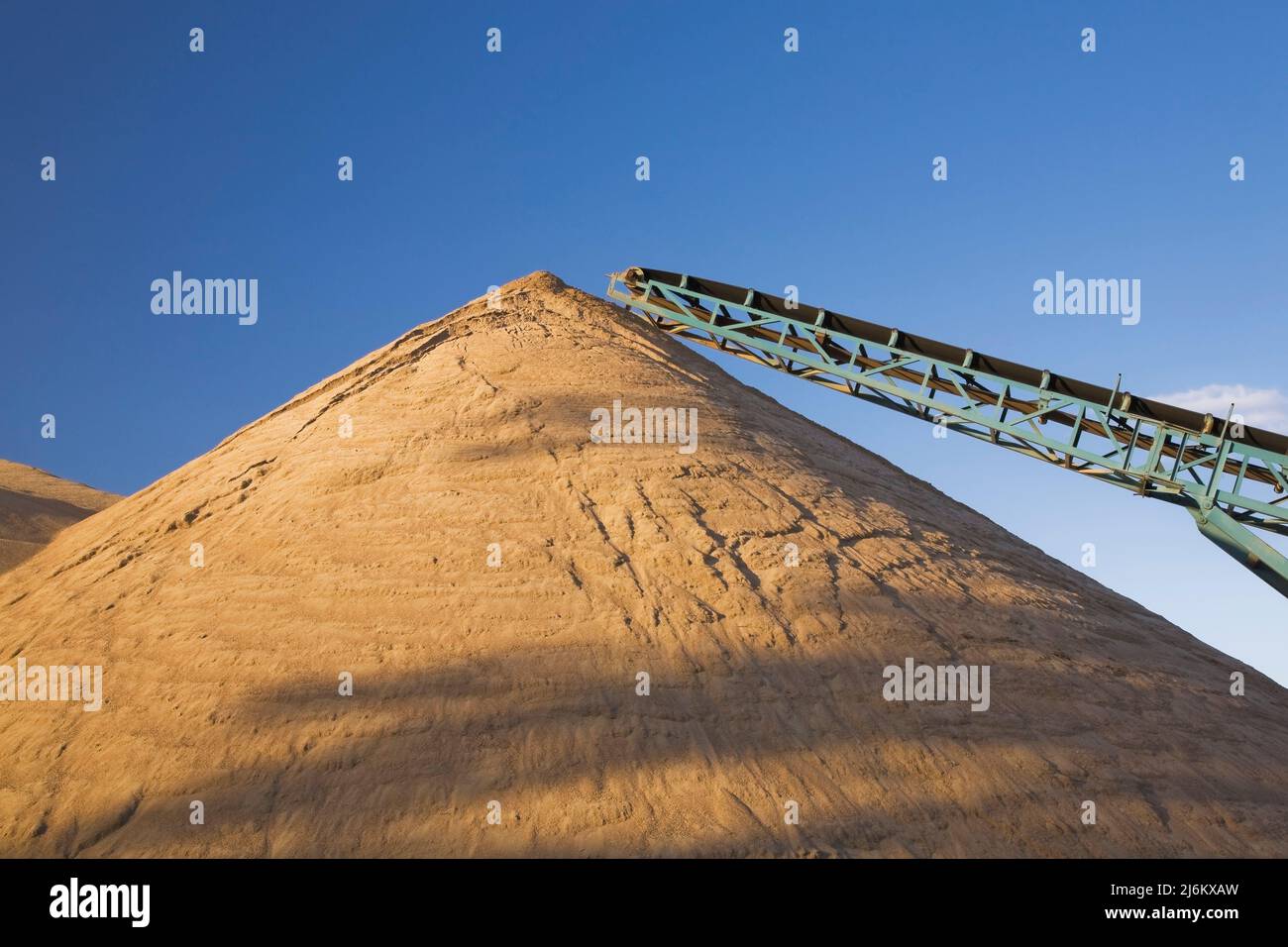 Mound of sand and stacking conveyor in commercial sandpit. Stock Photo