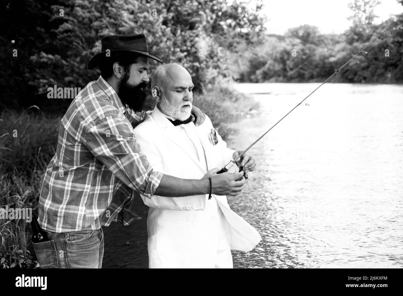 Family and generation - summer holidays and people concept. Man fisherman catches a fish. Brown trout fish. Happy father and son fishing in river Stock Photo