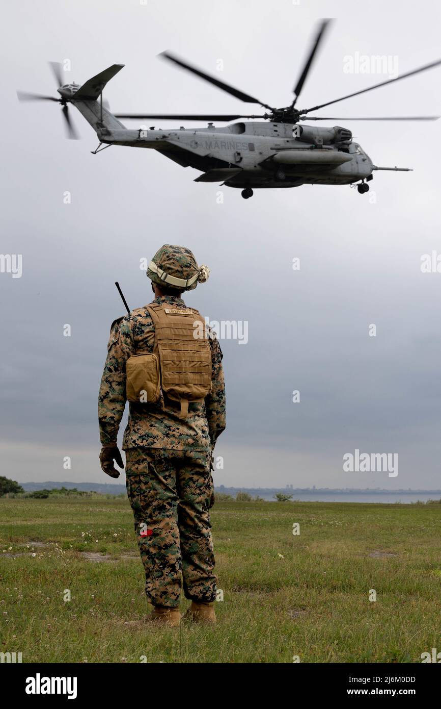 U.S. Marine Corps Sgt. Esequiel Lopezramirez, a landing support specialist with 3rd Landing Support Battalion, 3rd Marine Logistics Group, observes a CH-53E Super Stallion land on Torii Station, Okinawa, Japan, April 19, 2022. Marines with 1st MAW and 3rd MLG conducted helicopter support team (HST) training in preparation for joint service Expeditionary Advanced Base Operations. (U.S. Marine Corps photo by Lance Cpl. Tyler Andrews) Stock Photo