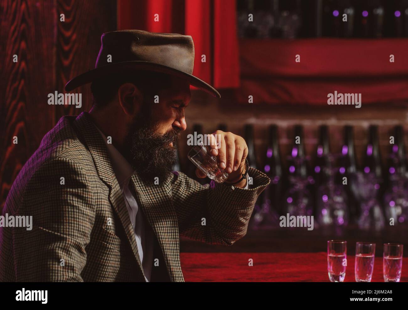 Handsome bearded man enjoying whiskey in bar. Hipster drinking in bar. Brutal guy drinking alcohol. Stock Photo
