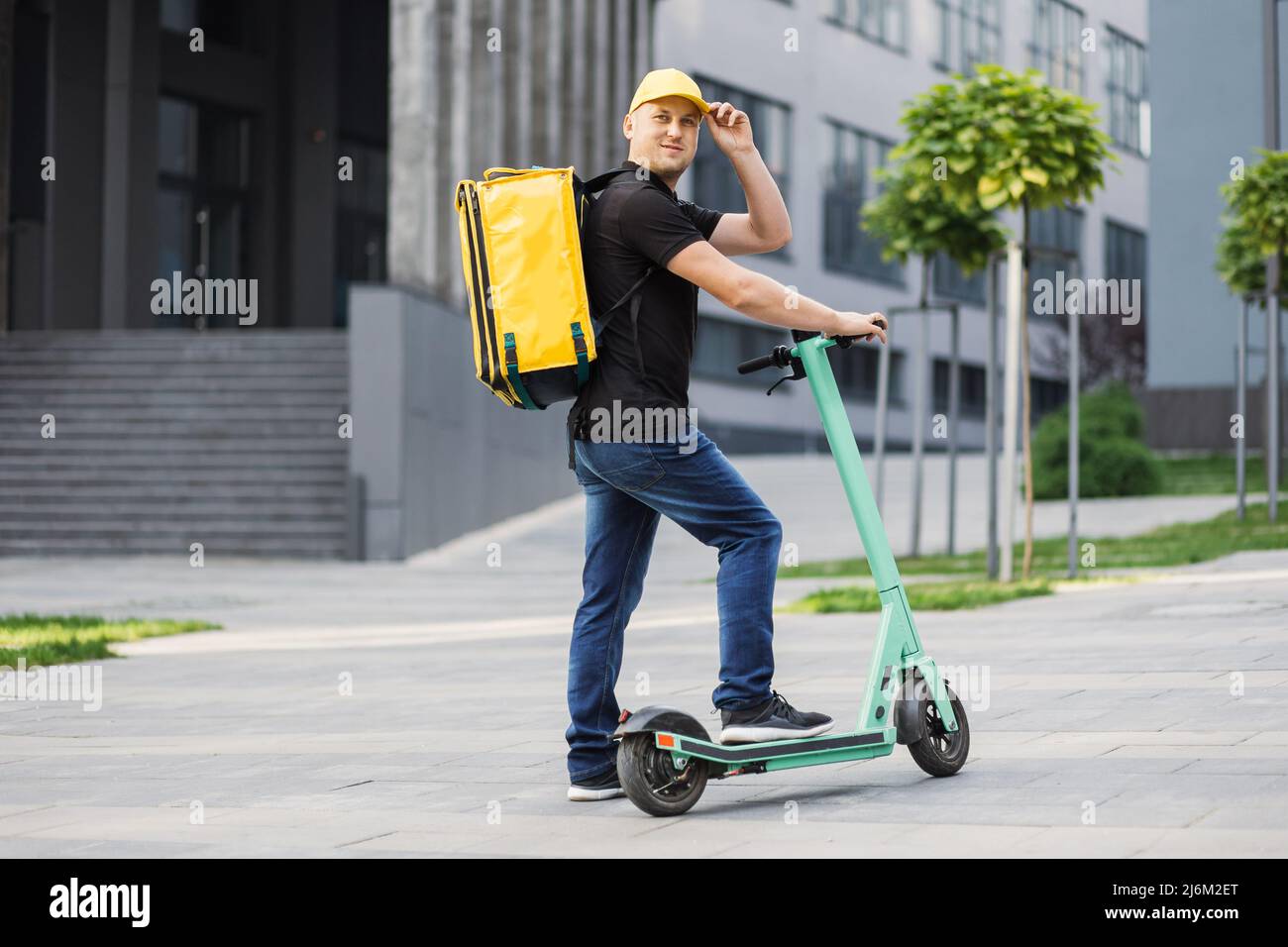 Courier deliver food on electric scooter. Boy delivering hot food to