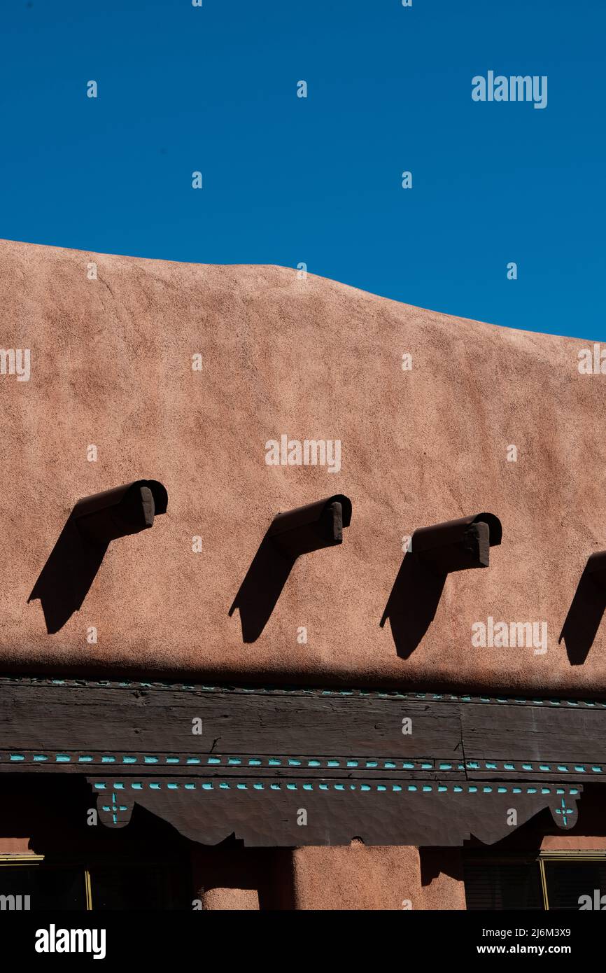 large wooden beams protruding from concrete exterior wall of adobe home or house in Santa Fe, New Mexico, U.S.A. Adobe architecture construction Stock Photo