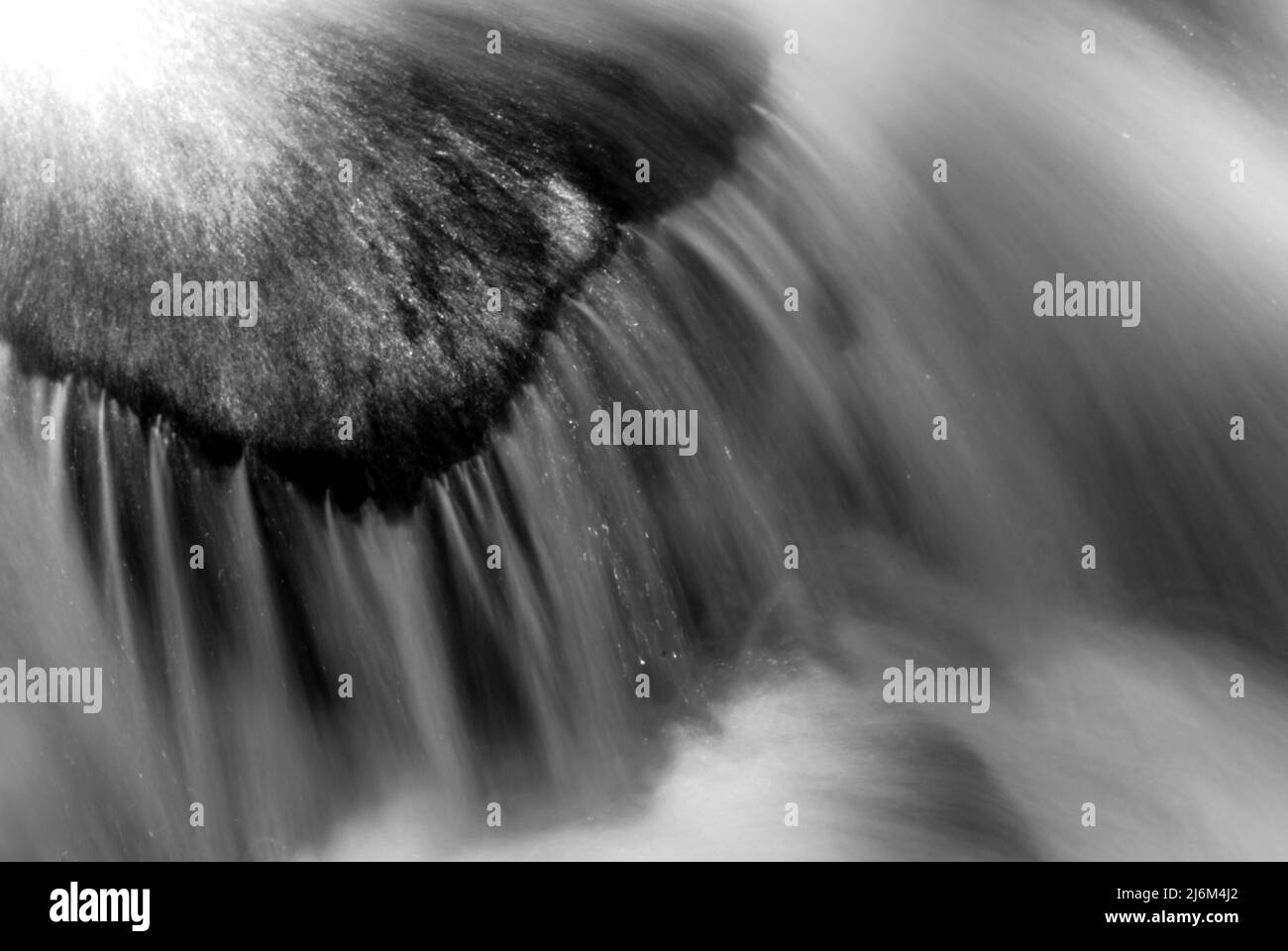 Black and white photo of water rushing over a rock Stock Photo - Alamy