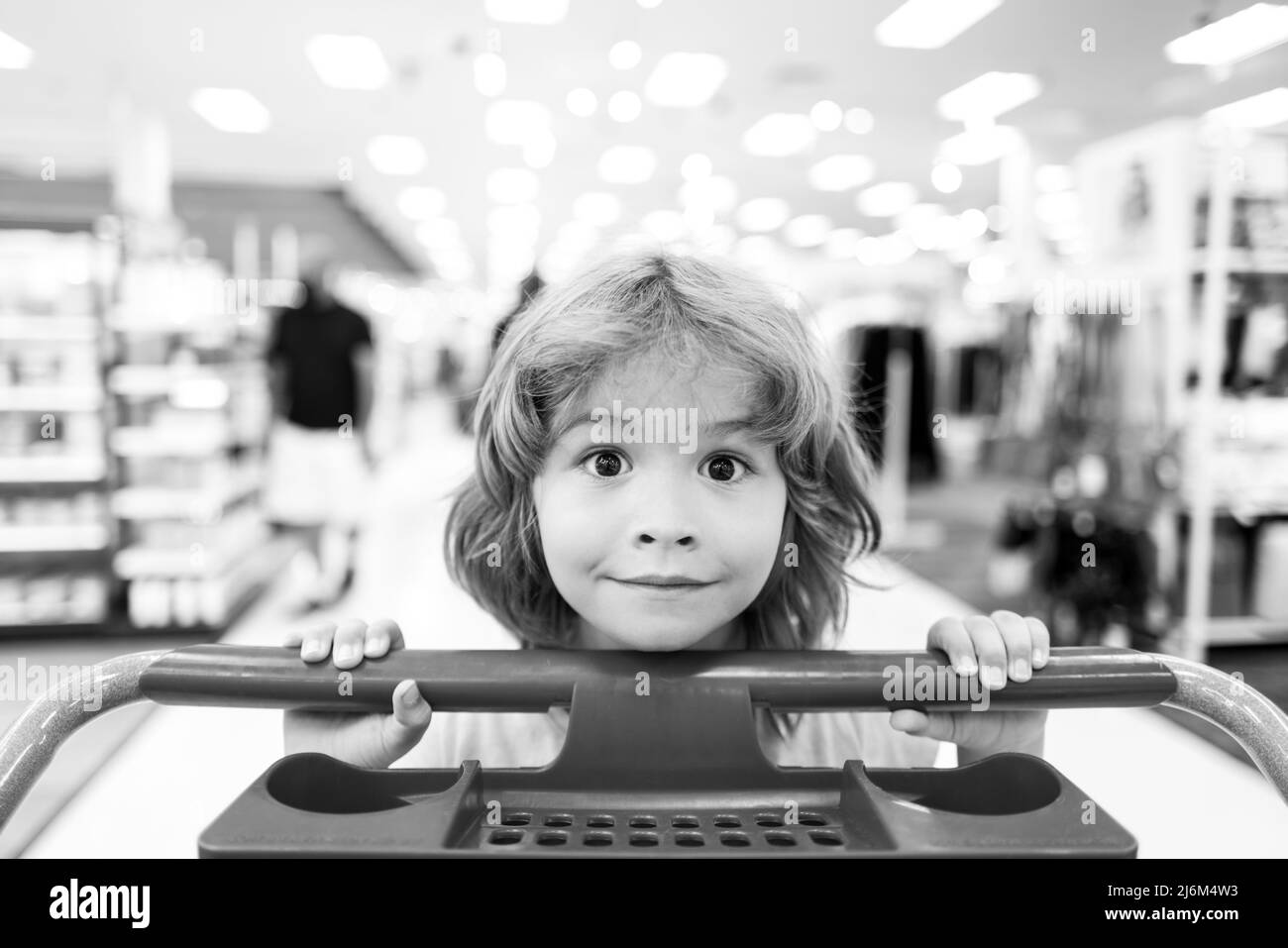 Child with shopping cart in a grocery store. Funny kid with shopping