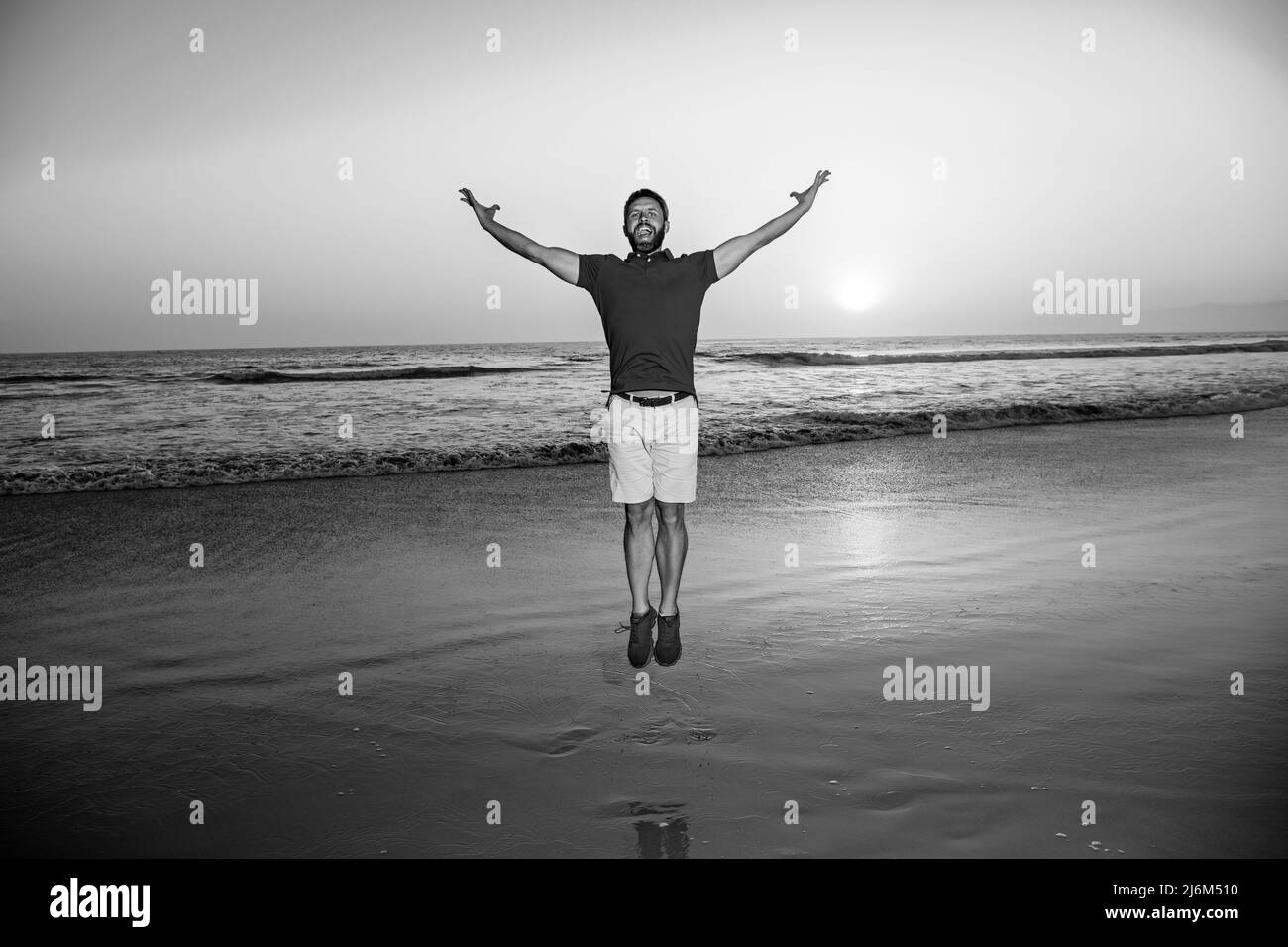 Man jumping on beach, silhouette in the sunset. Amazing view on sunset beach. Stock Photo