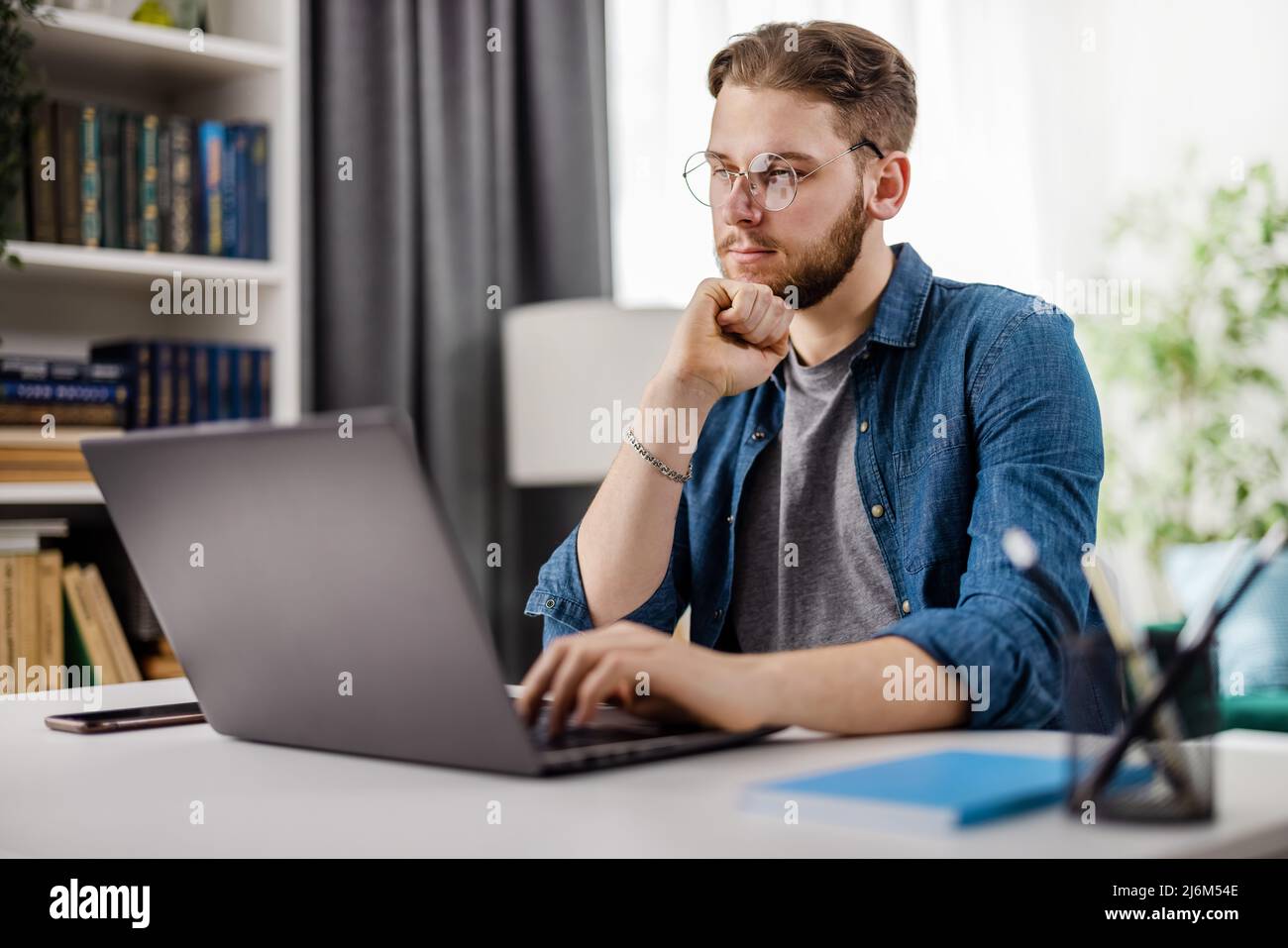 Thoughtful man with laptop at home Stock Photo