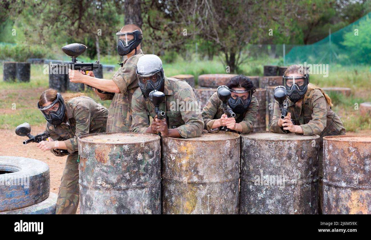 Group of paintball players aiming and shooting with guns Stock Photo
