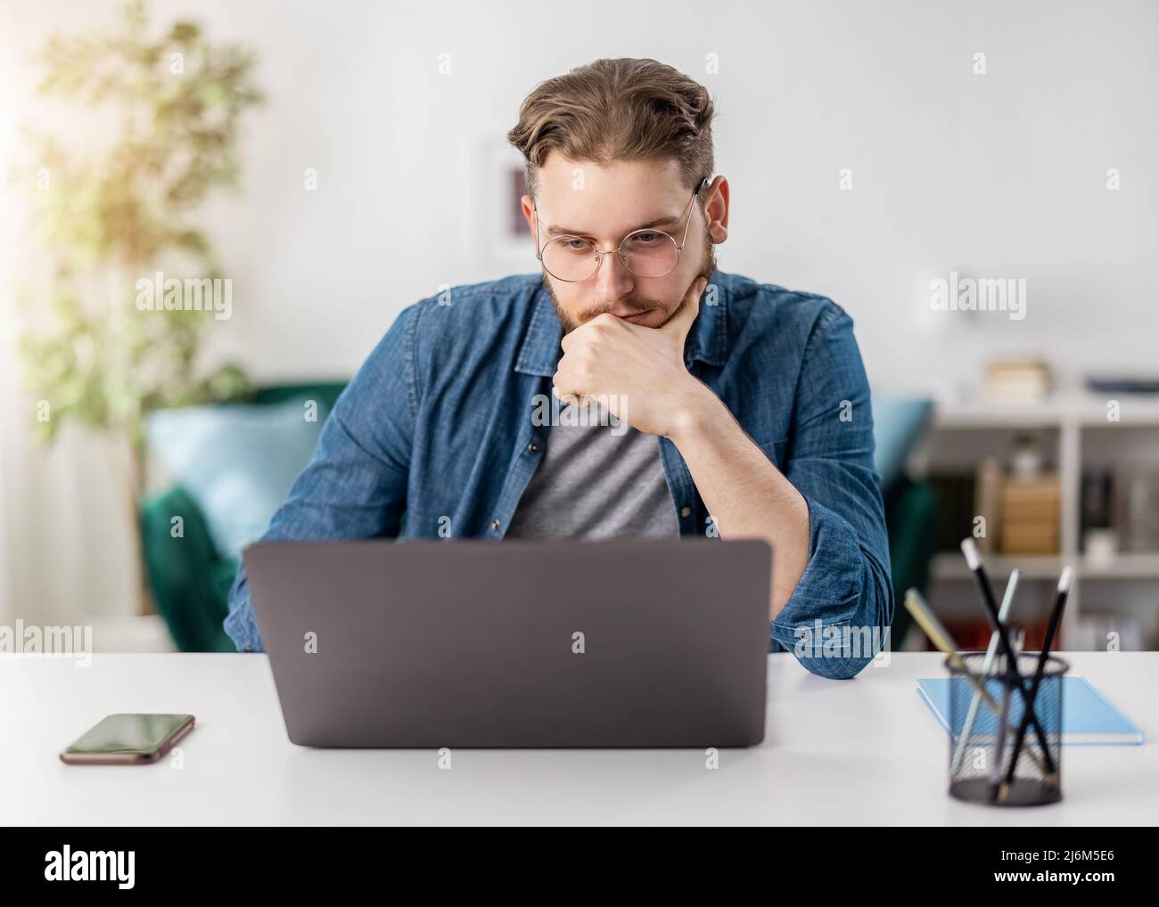 Pensive man with laptop at home Stock Photo
