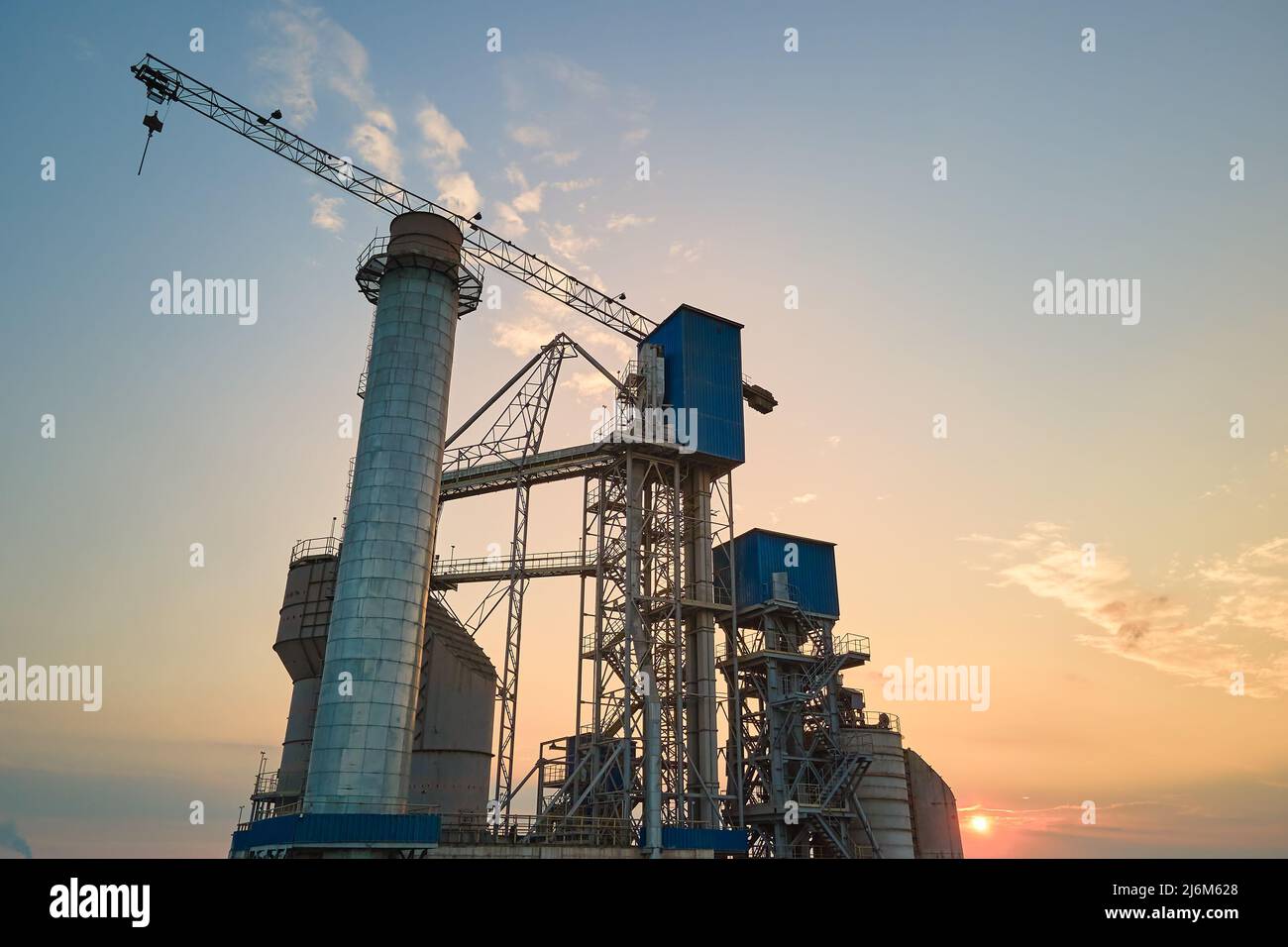 Aerial view of cement factory with high concrete plant structure and tower crane at industrial production site. Manufacture and global industry Stock Photo