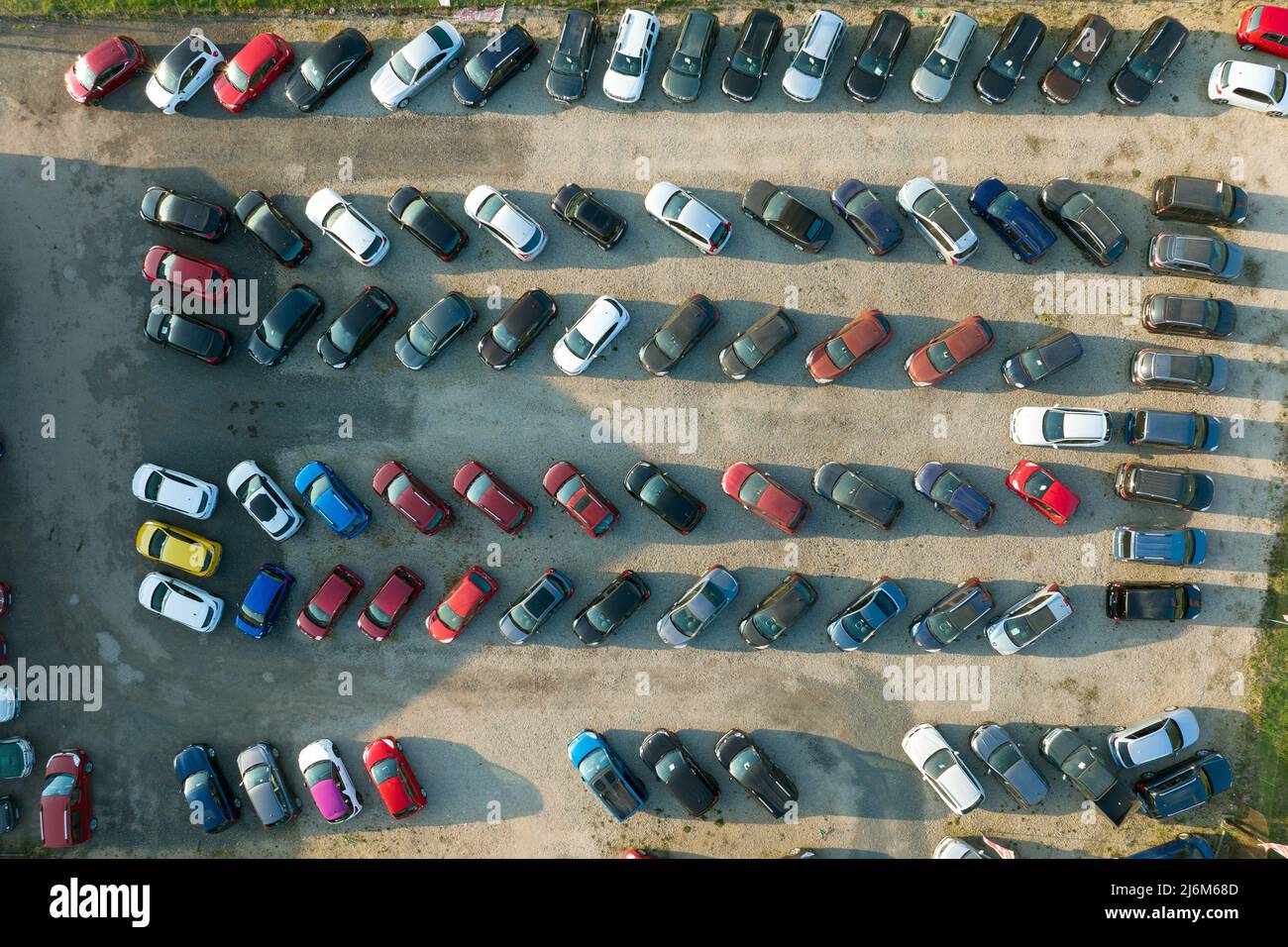 Aerial view of many colorful cars parked on dealer parking lot for sale