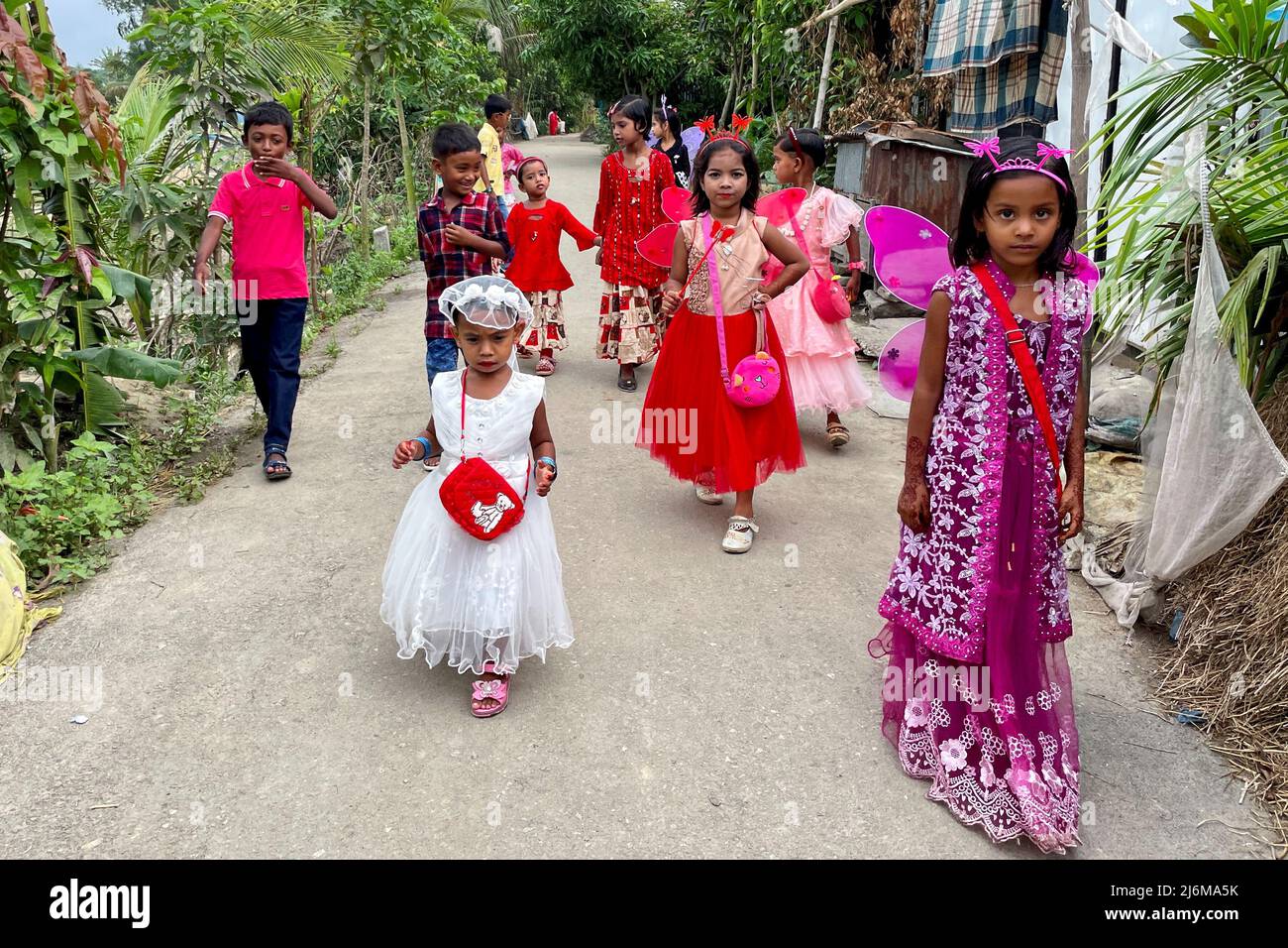 Children walk down a road wearing new dresses on the day of Eid-al-fitr in Munshiganj, Bangladesh, May 3, 2022. REUTERS/Mohammad Ponir Hossain Stock Photo