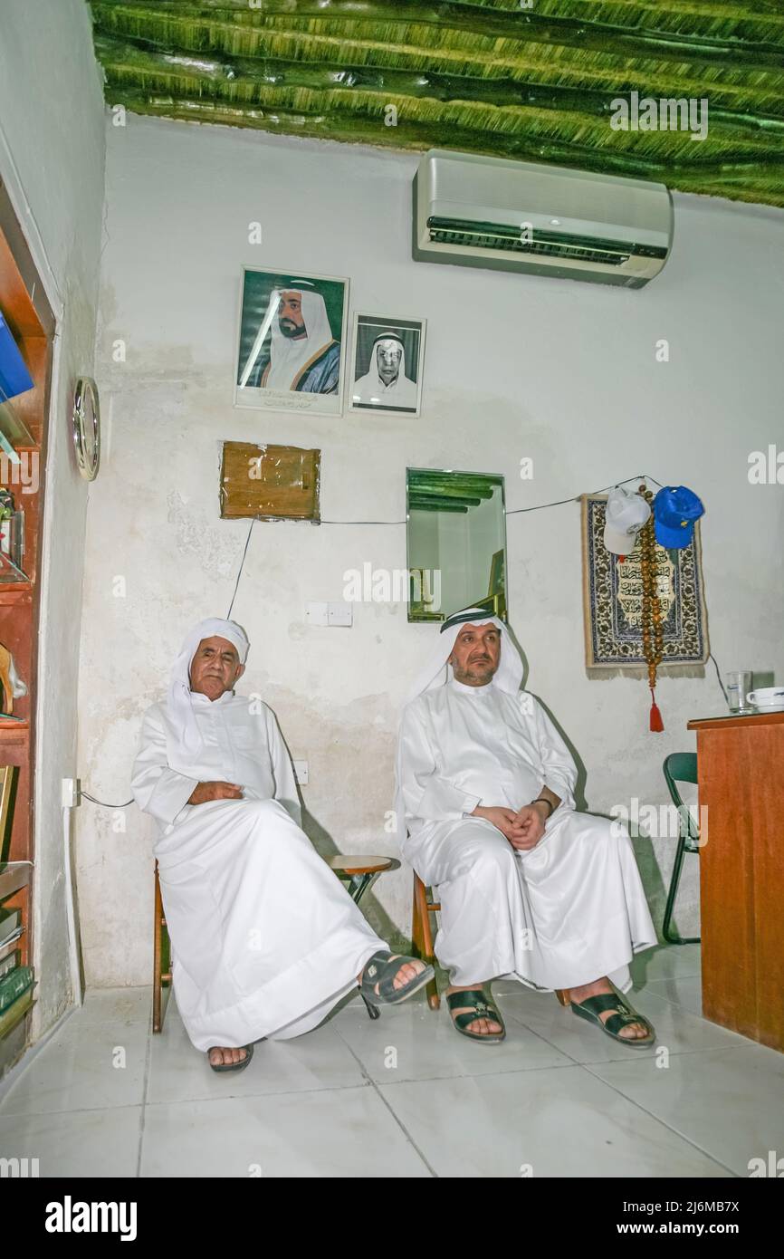 Two Arab men relaxing in a room in the city of Sharjah's Heritage Area Souk in the United Arab Emirates. Stock Photo