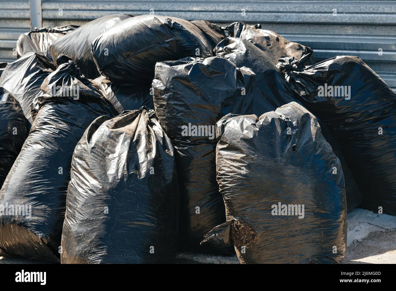 Many large black bags of garbage stand outside in garbage. Cleaning of territory. Let's make world cleaner. Background. Stock Photo