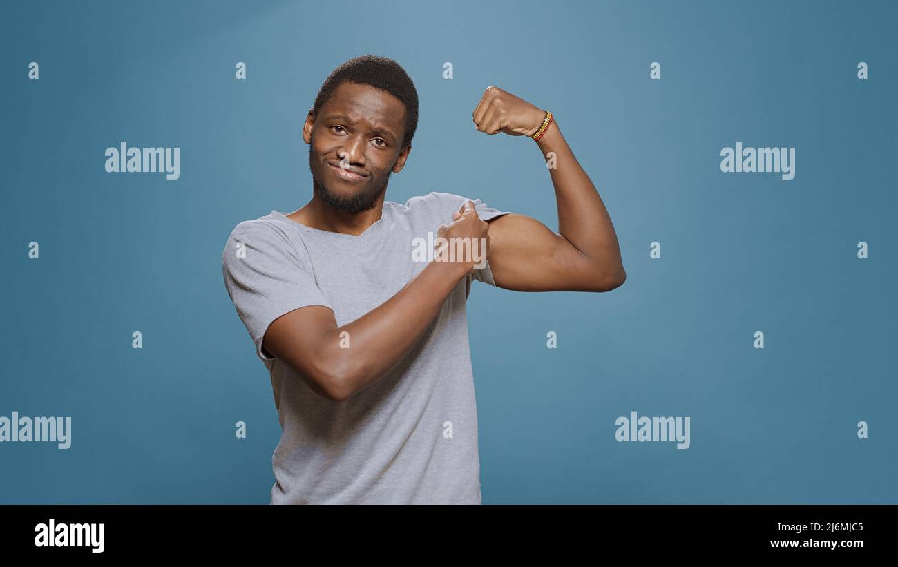 Athletic person flexing biceps and triceps muscles on camera showing muscular fitness and masculinity. Young fit man expressing endurance and bodybuilding technique. Powerful sportsman Stock Photo Ala...