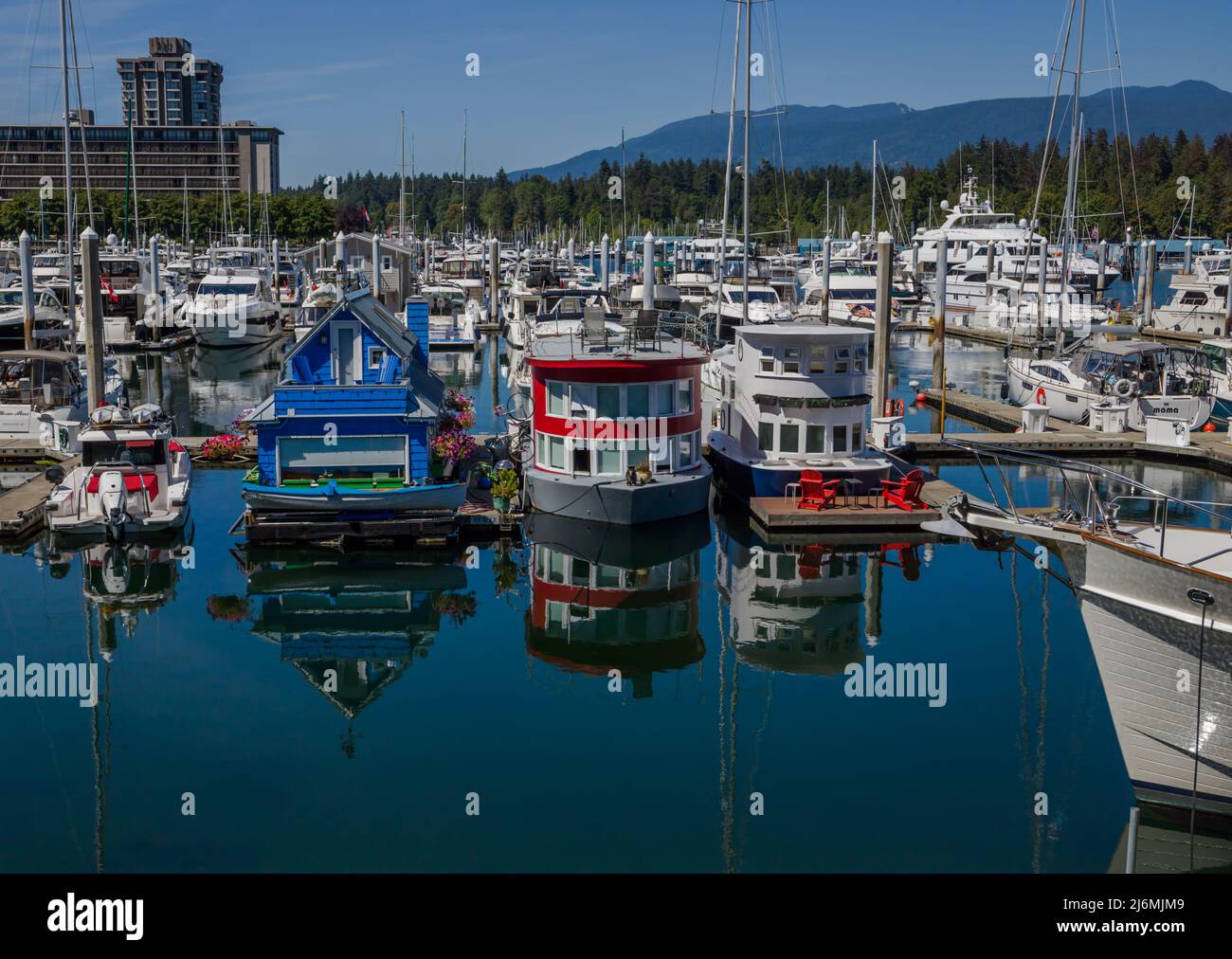 Cute, colourful floating houseboats line the docks with calm water reflections. This alternative housing is growing in popularity with a challenging h Stock Photo