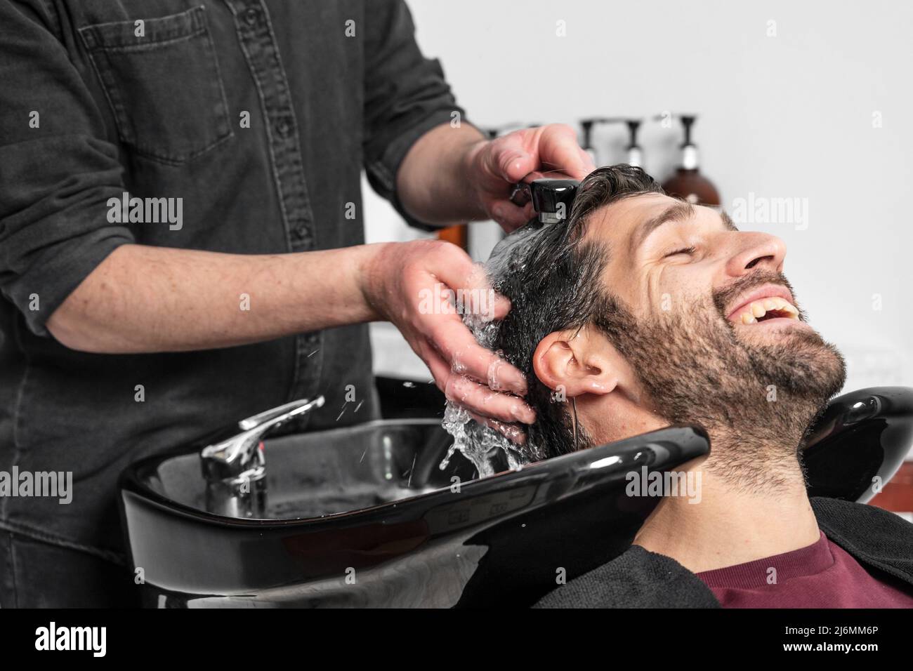 Barber shop. Hairdresser man washes client head in High