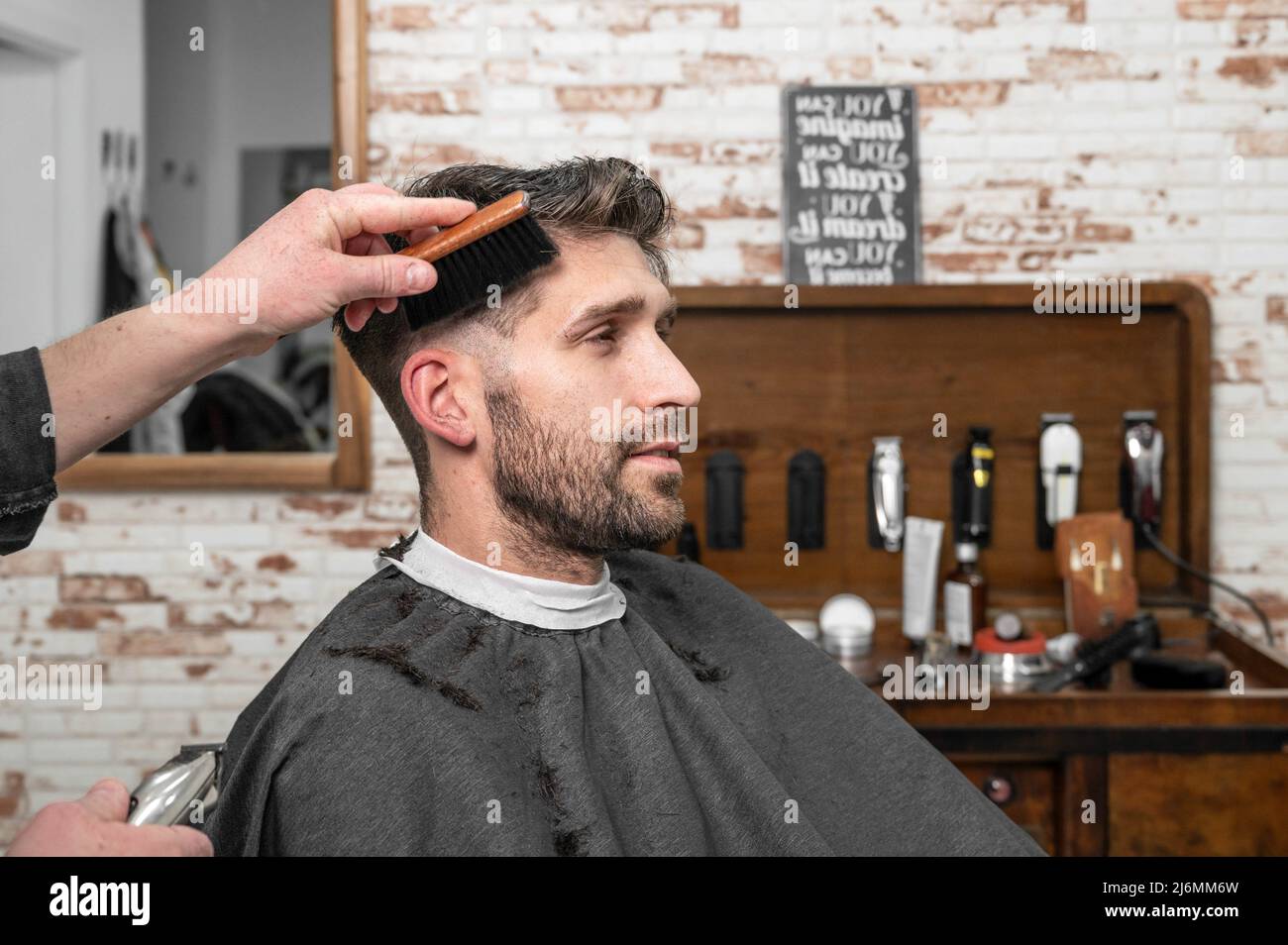 Shot of a barber using a brush on his client's beard. High quality photography. Stock Photo