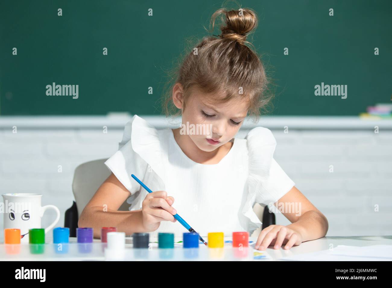 Little girls drawing a colorful pictures with pencil crayons in school ...
