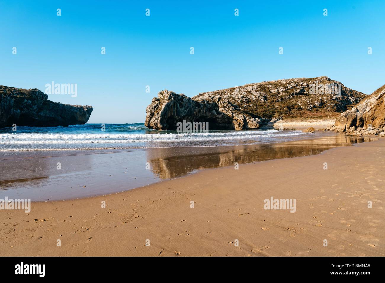 Beach of Cuevas del Mar, Caves of the sea, Llanes, Asturias, Spain. Long exposure, sunny day with bright blue sky. Stock Photo