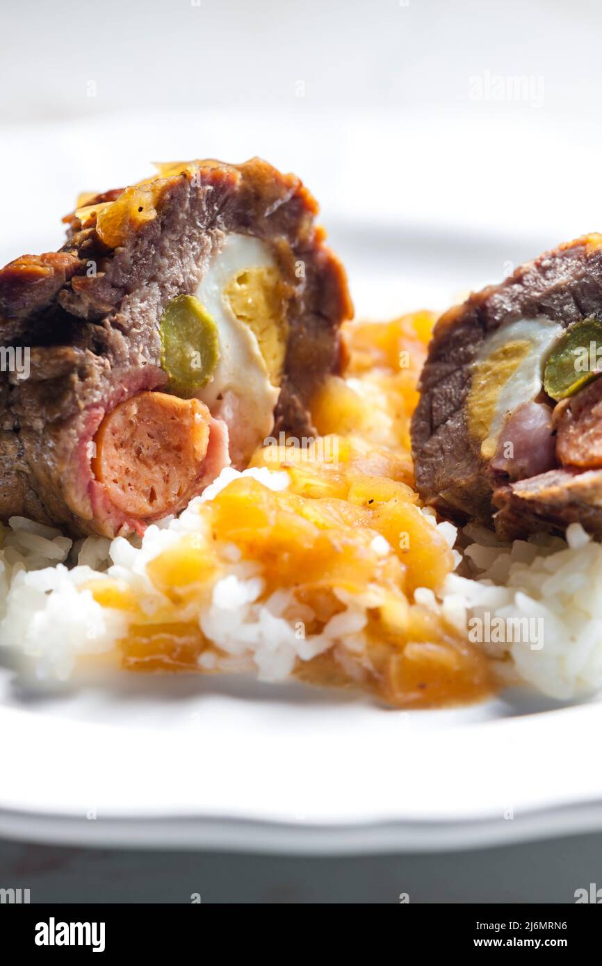 beef roulade filled with egg, sausage, bacon and prickle served with rice. Stock Photo