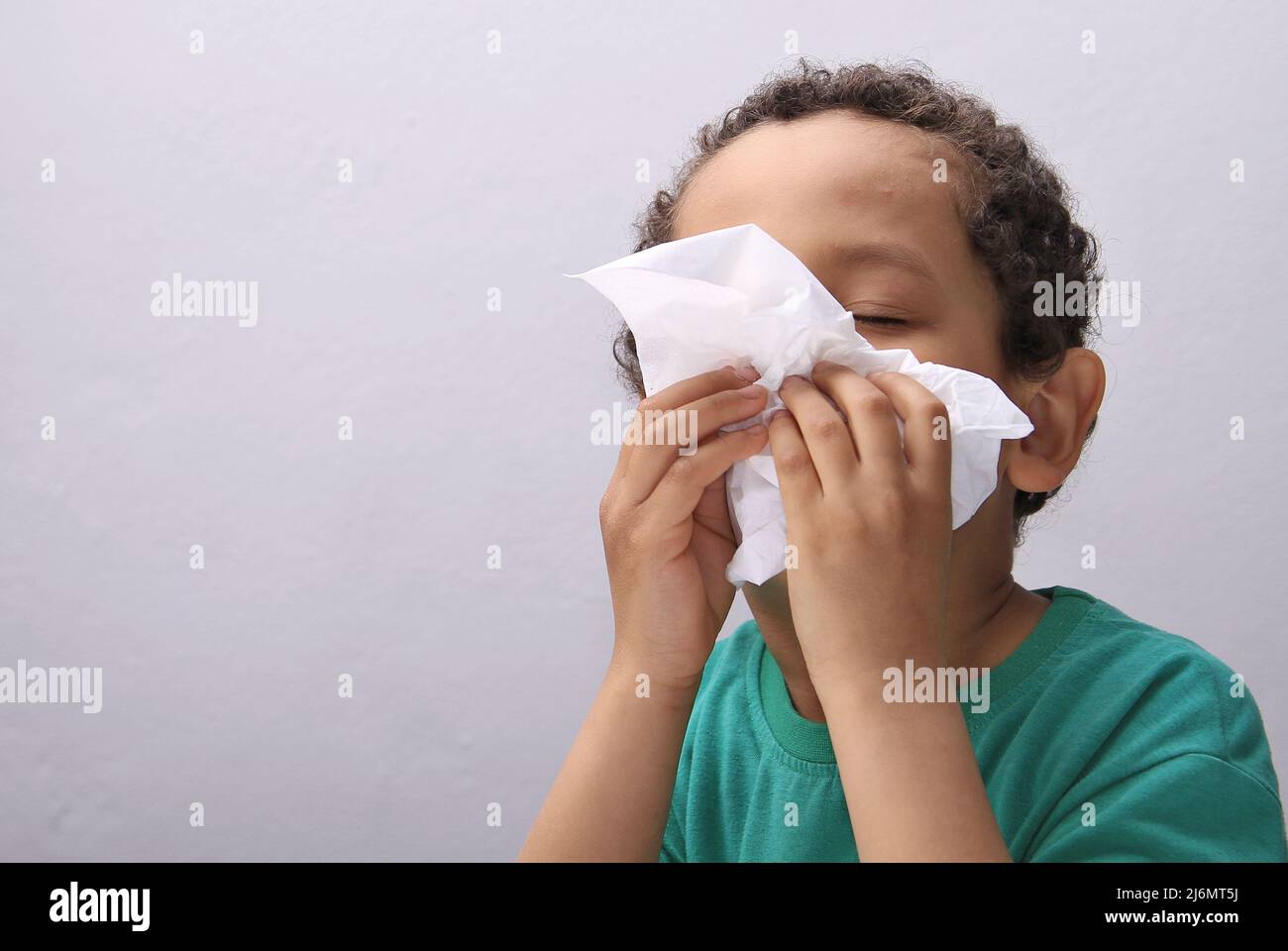 catching the flu child blowing nose after catching a cold with grey