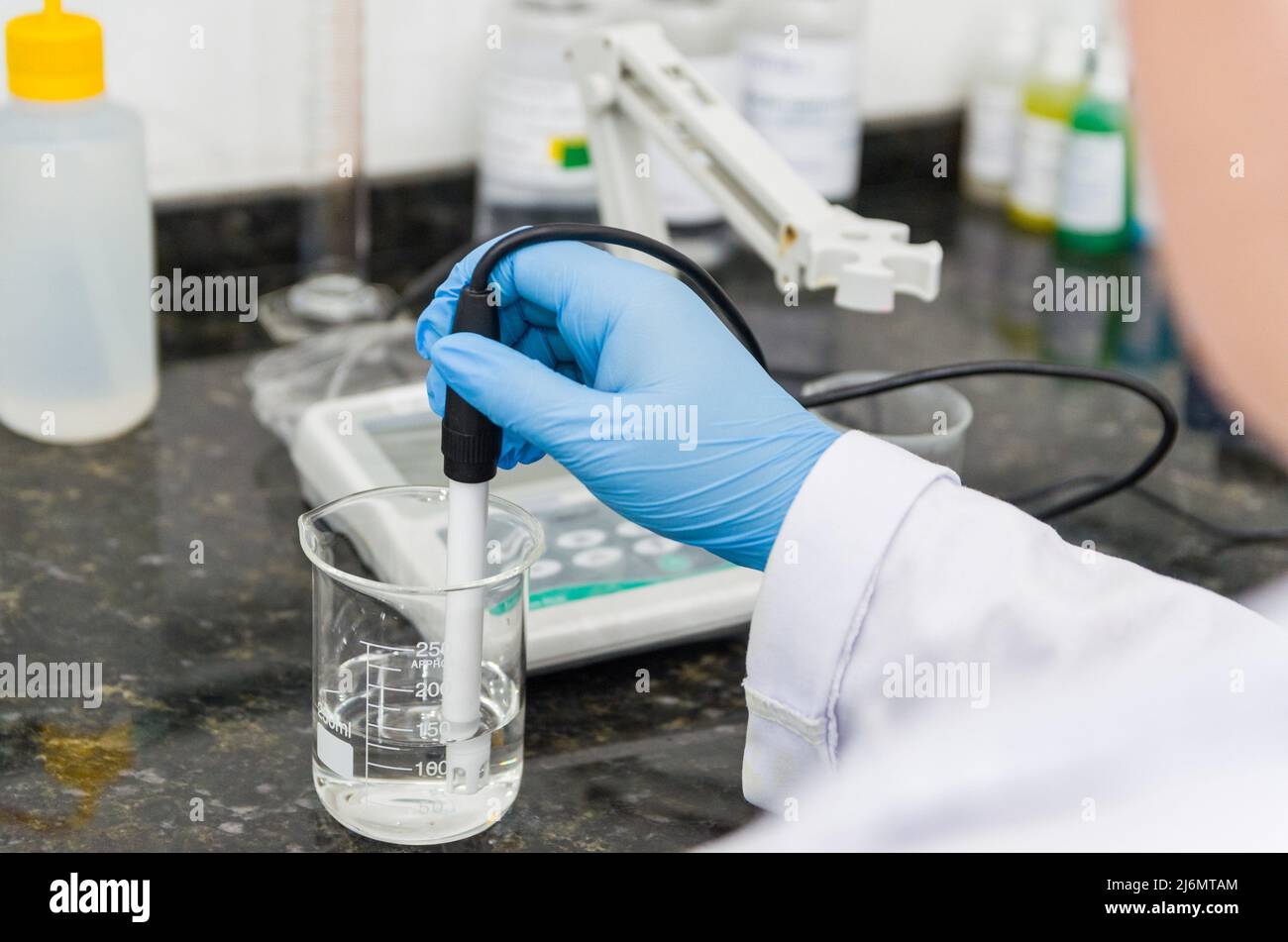 Woman hands performing pH test on pH meter electronic instrument for quality control in chemical
