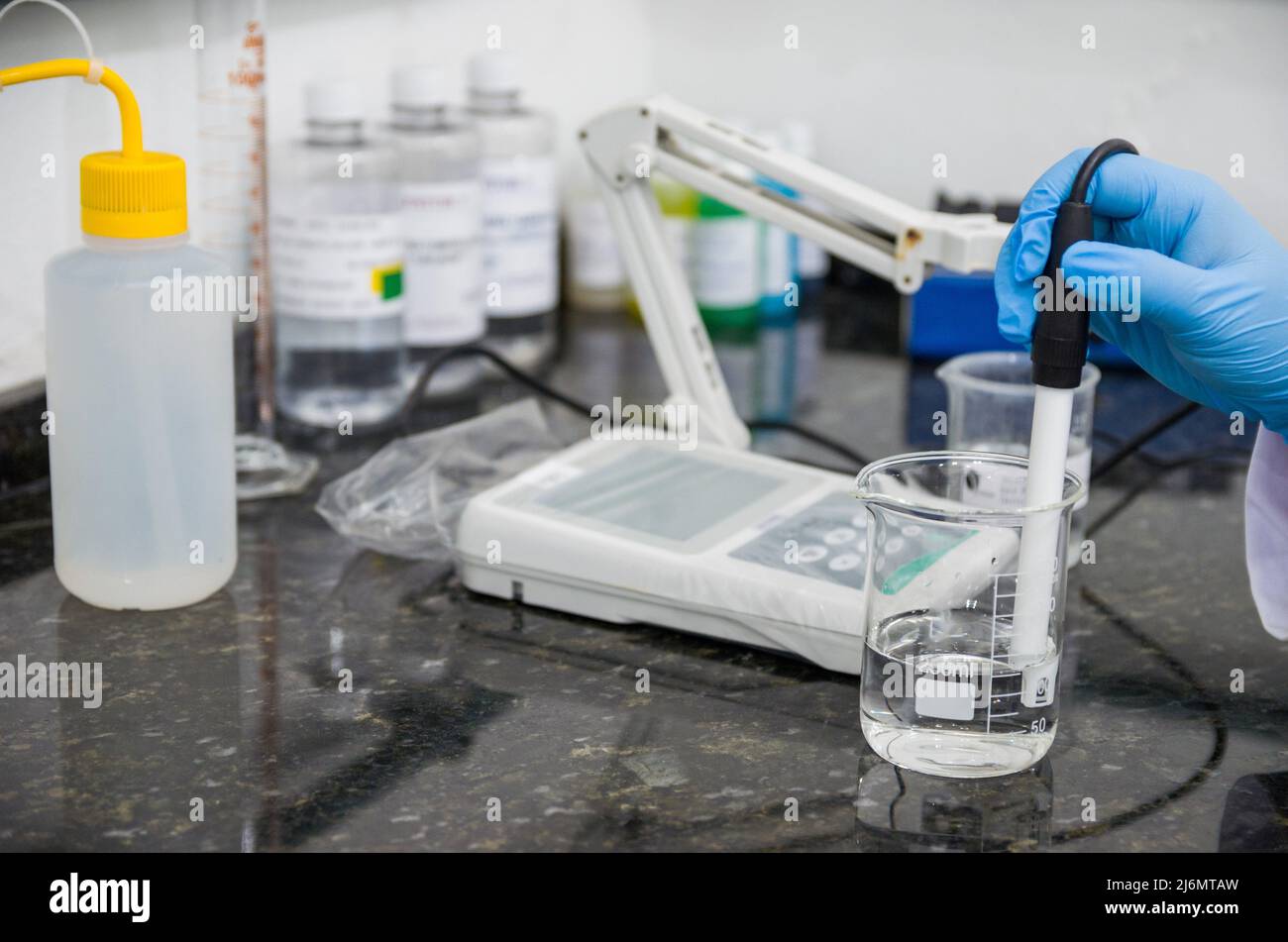 Woman hands performing pH test on pH meter electronic instrument for