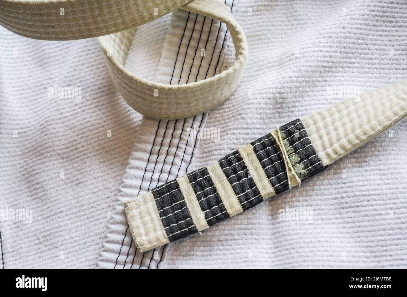 White belt of Brazilian JiuJitsu with four degrees, on top of the