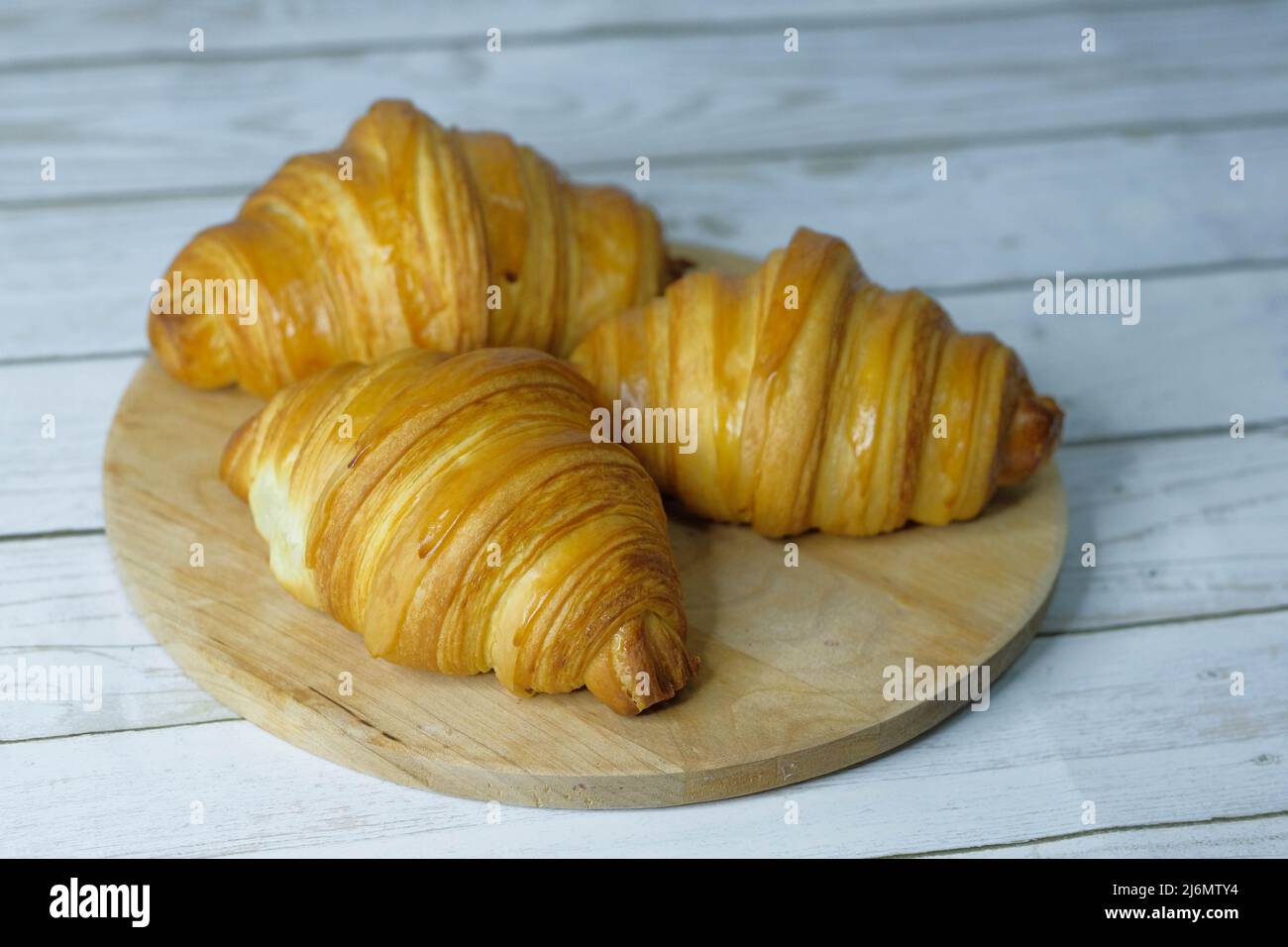 Some fresh croissants on a wooden surface Stock Photo