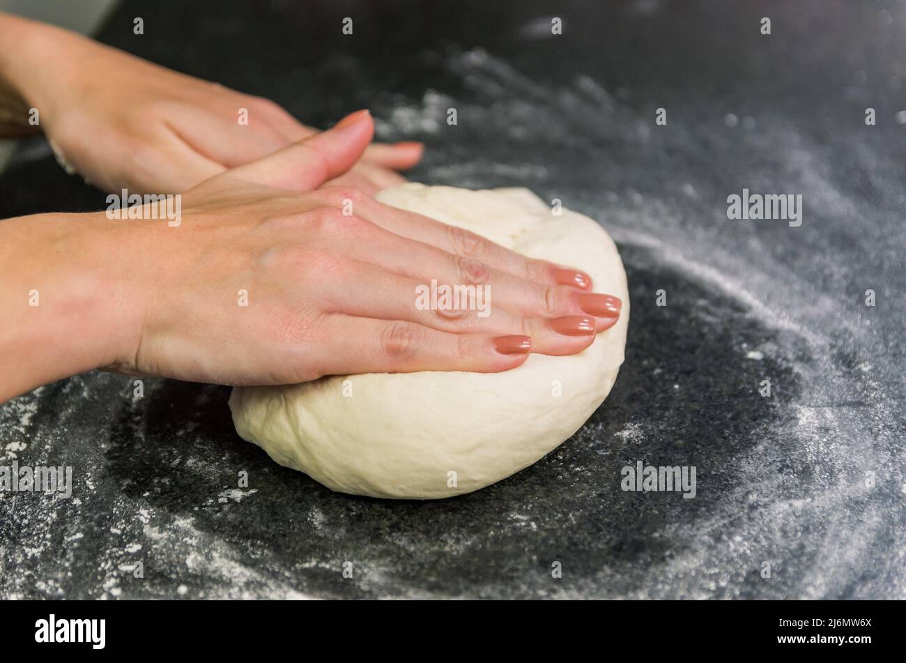 Woman preparing pizza dough on black granite table Stock Photo - Alamy